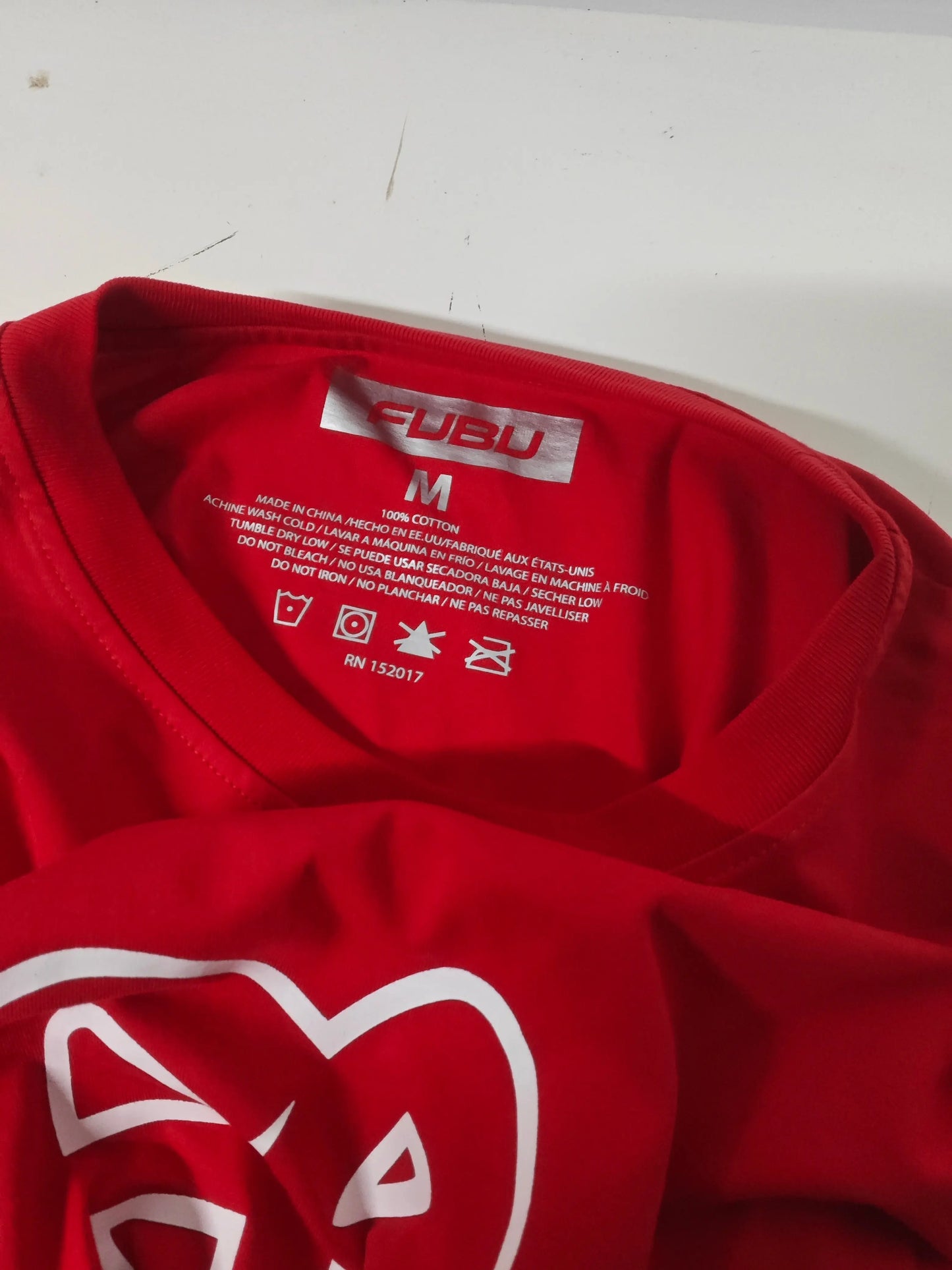 T-shirt rouge taille M de Fubu, avec étiquette d'entretien visible et logo imprimé.
