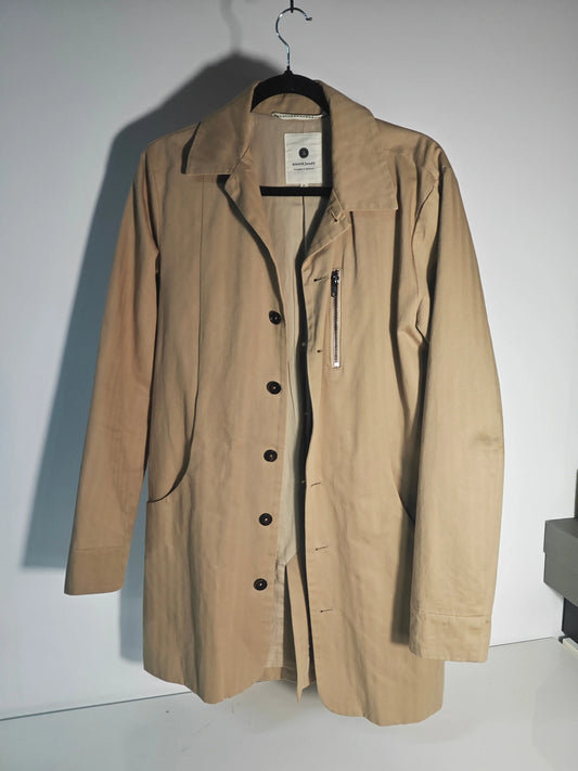 Manteau trench beige de Anerkjendt avec fermeture boutonnée, poche zippée, sur un cintre.