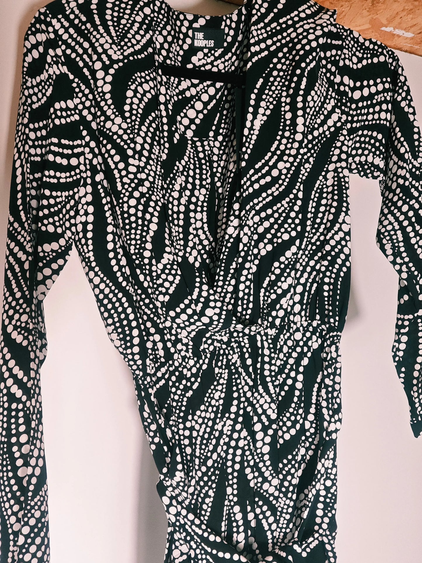 Robe combi noire à pois blancs de The Kooples, avec encolure cache-cœur et manches longues.
