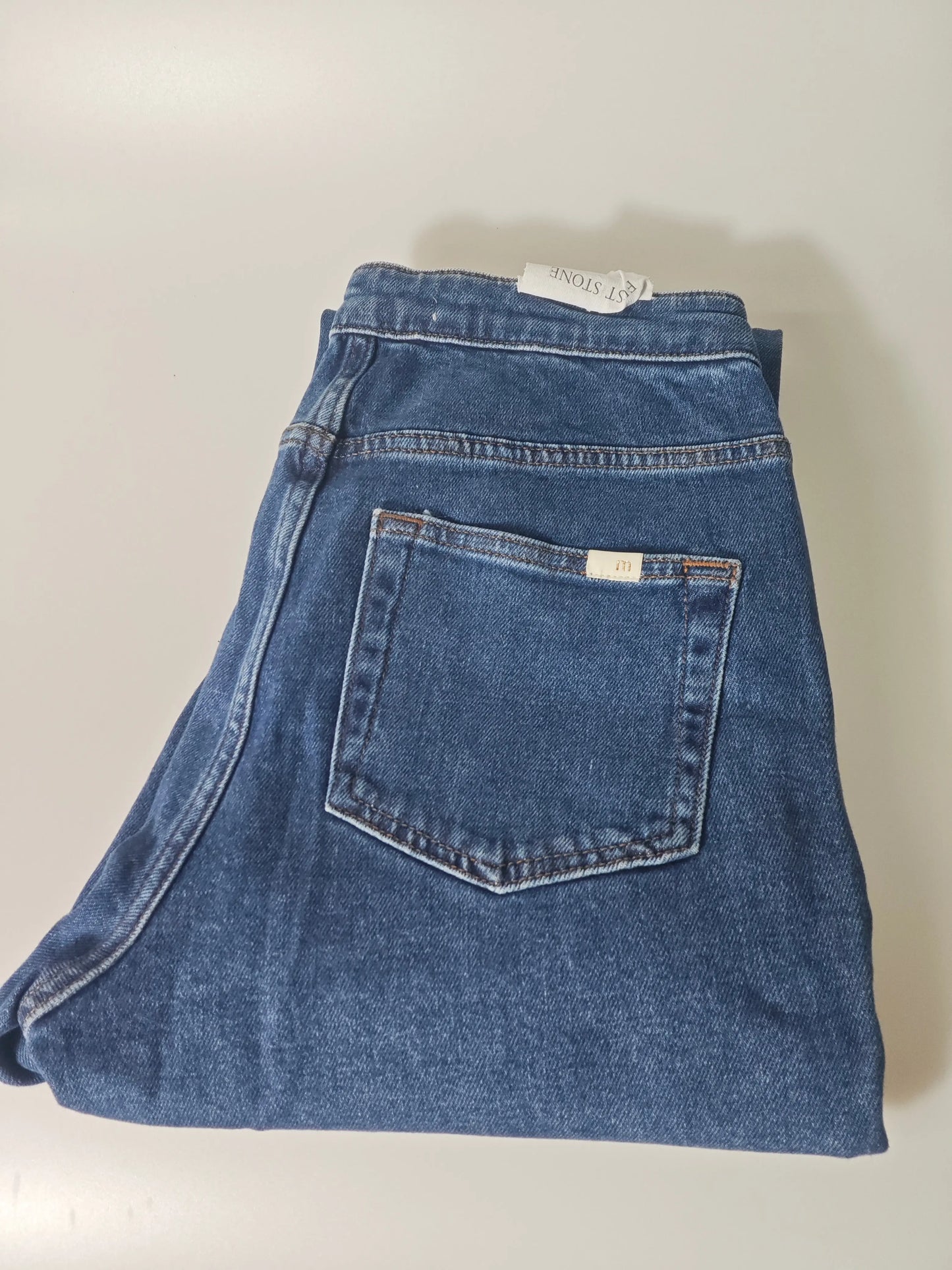 Jean bleu taille 38 de Maje, plié, avec poche arrière carrée et étiquette blanche apparente.
