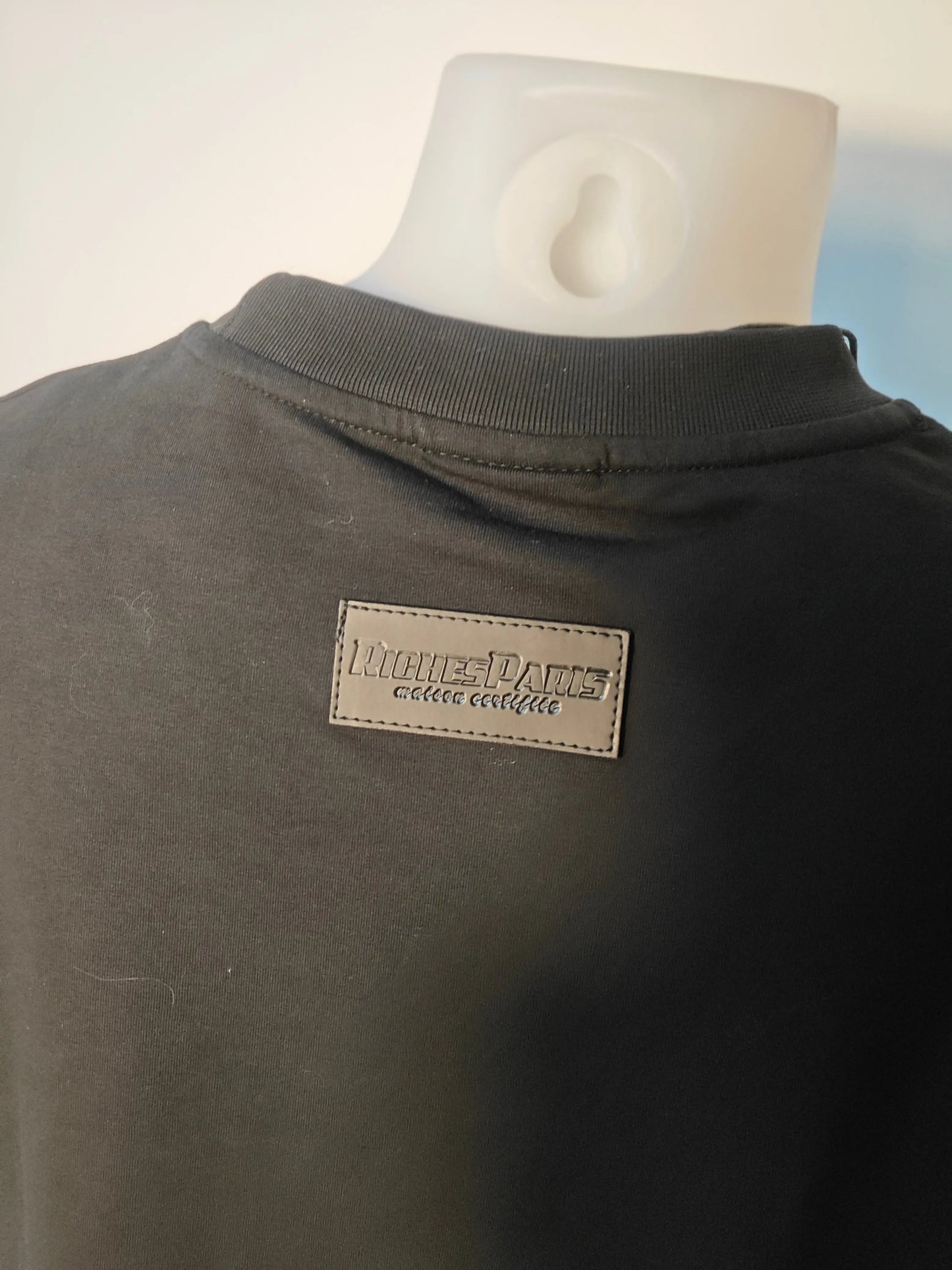 T-shirt noir de Riches Paris, avec un écusson logo en cuir à l'arrière du cou.