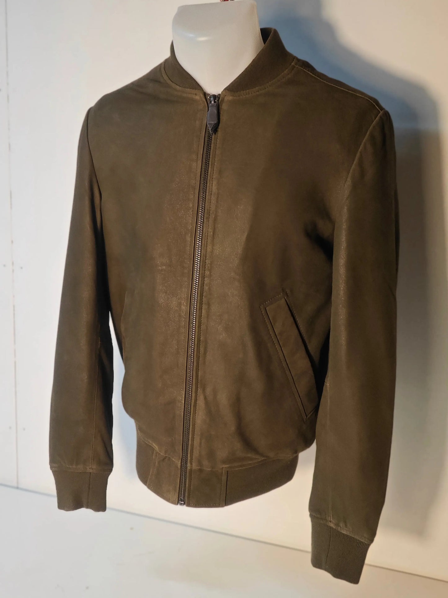 Blouson en cuir kaki IKKS, avec fermeture éclair et manches longues resserrées.