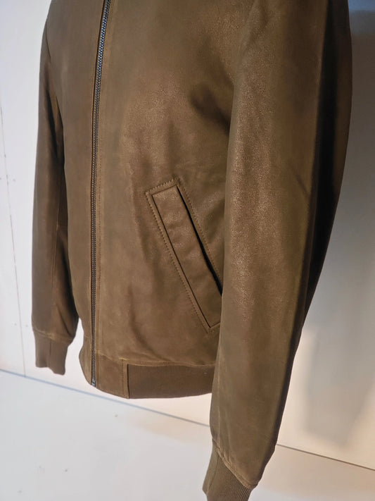 Blouson en cuir kaki par IKKS, avec fermeture éclair et poche passepoilée.