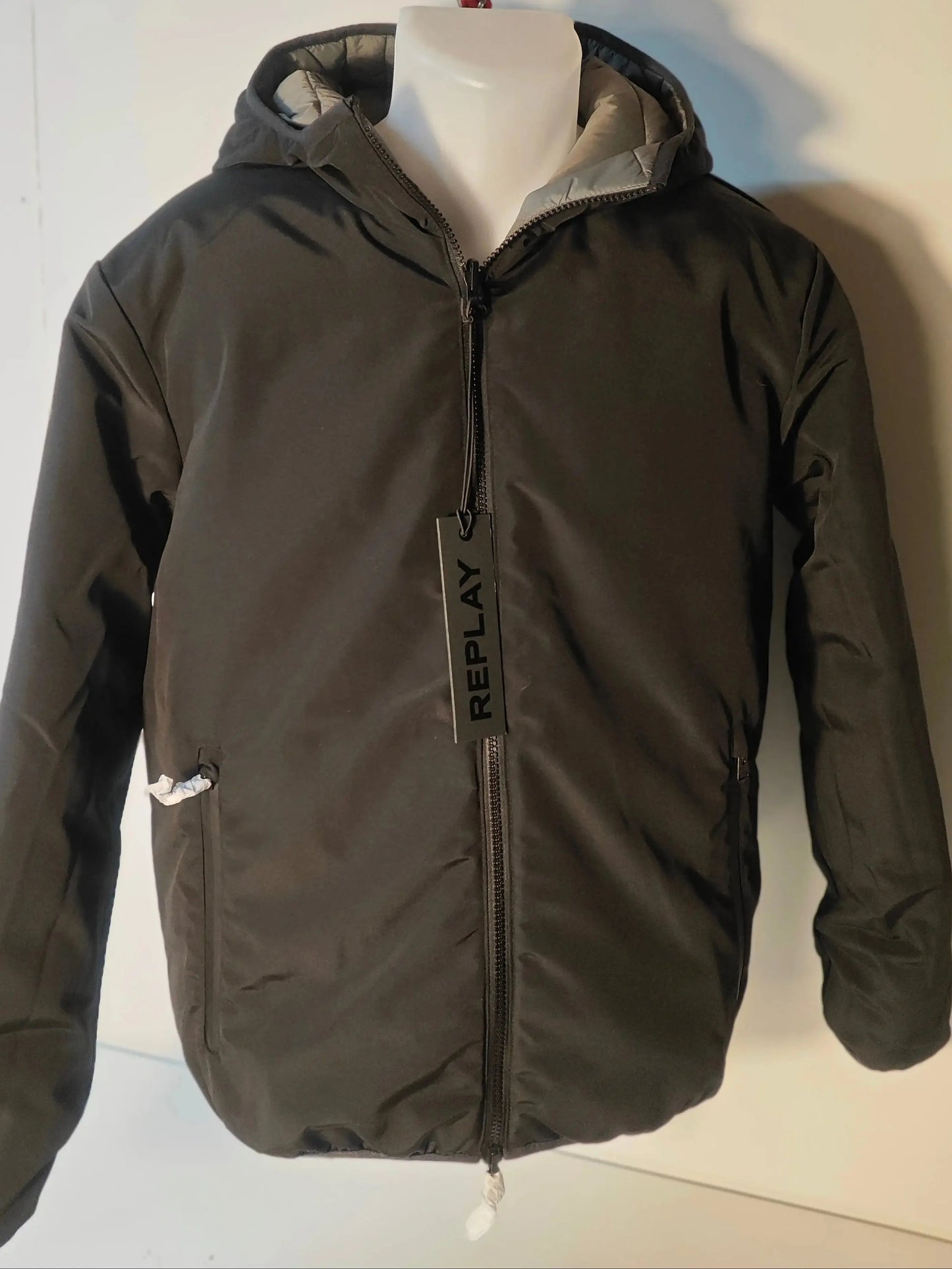 Veste réversible kaki et noire de Replay avec capuche et étiquette de la marque.