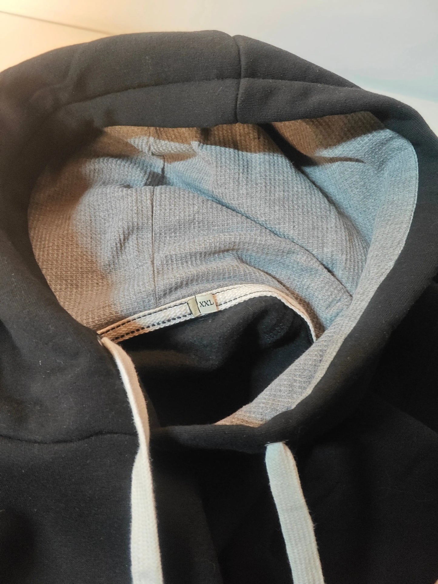 Hoodie noir de The Garden, taille XXL, avec capuche grise et cordons blancs.