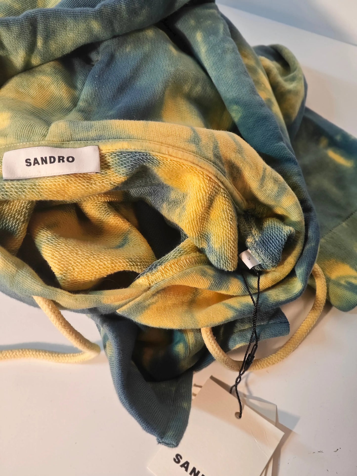 Sweat à capuche tie and dye bleu et jaune, de Sandro, avec cordon de serrage et étiquette de taille.
