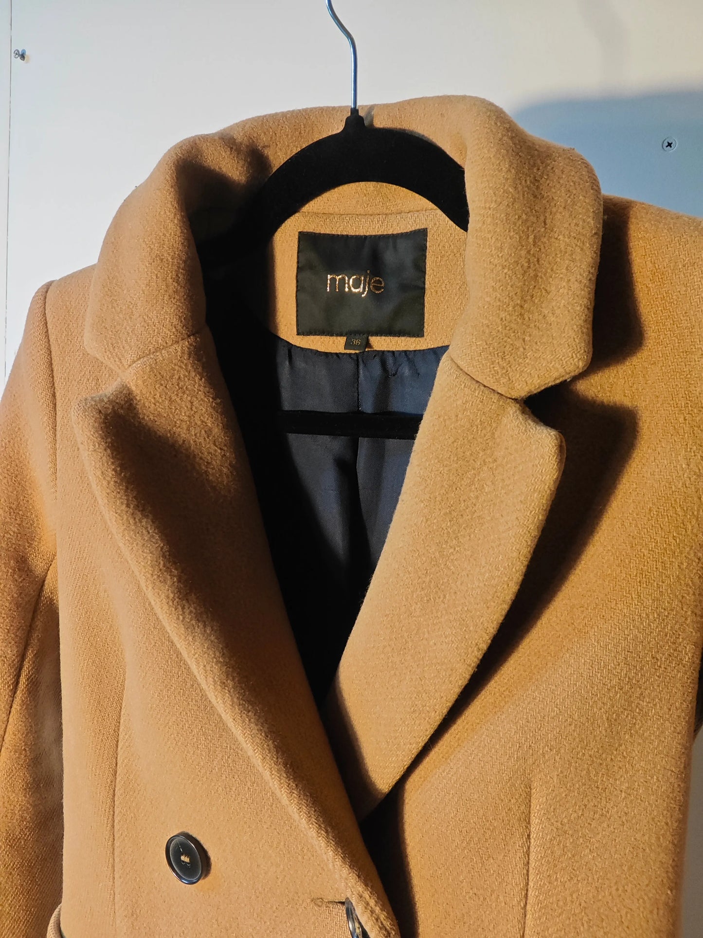 Manteau camel de chez Maje, coupe longue croisée avec double boutonnage et col tailleur.
