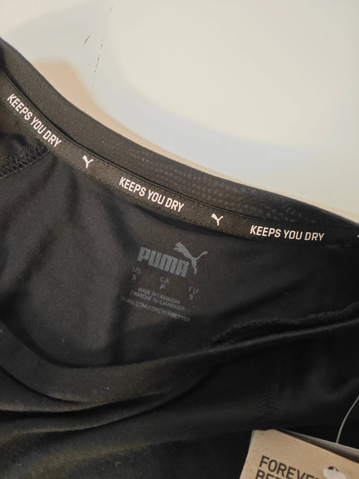 T-shirt noir à logo argent DRYCELL de Puma, avec étiquette de taille et inscription « Keeps You Dry ».