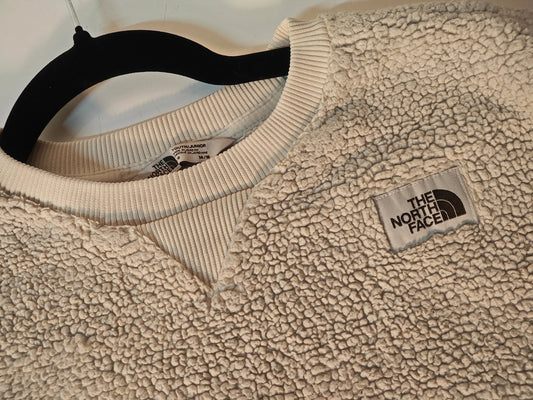Pull en polaire sherpa beige de The North Face, avec col rond côtelé et logo rectangulaire.