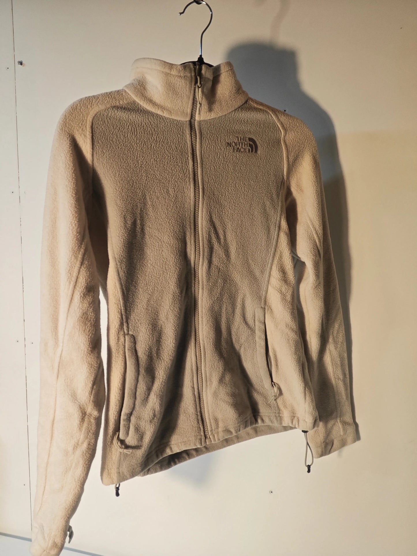Polaire beige en polaire, de The North Face, avec fermeture éclair et poches zippées.