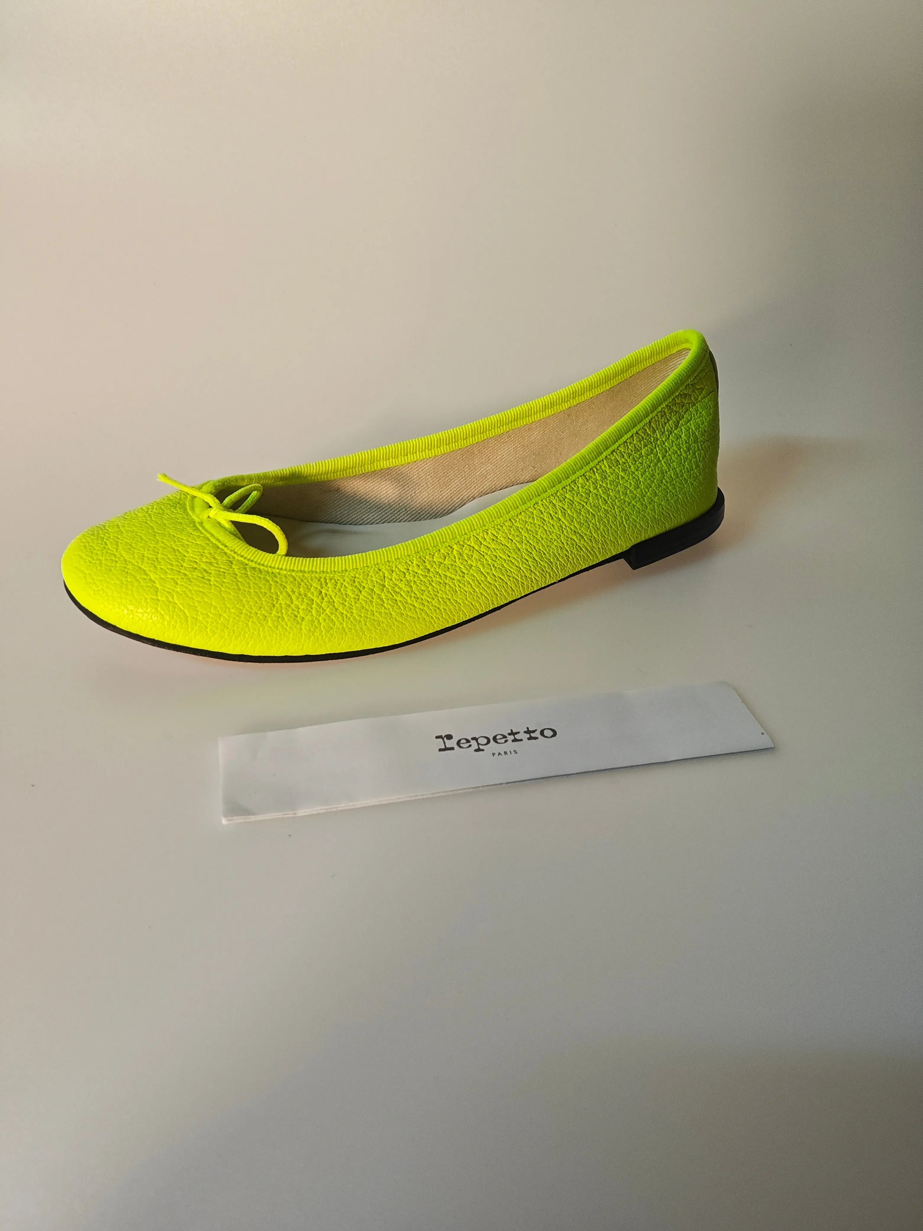 Ballerine jaune vif de Repetto, avec un petit noeud décoratif et une semelle noire.
