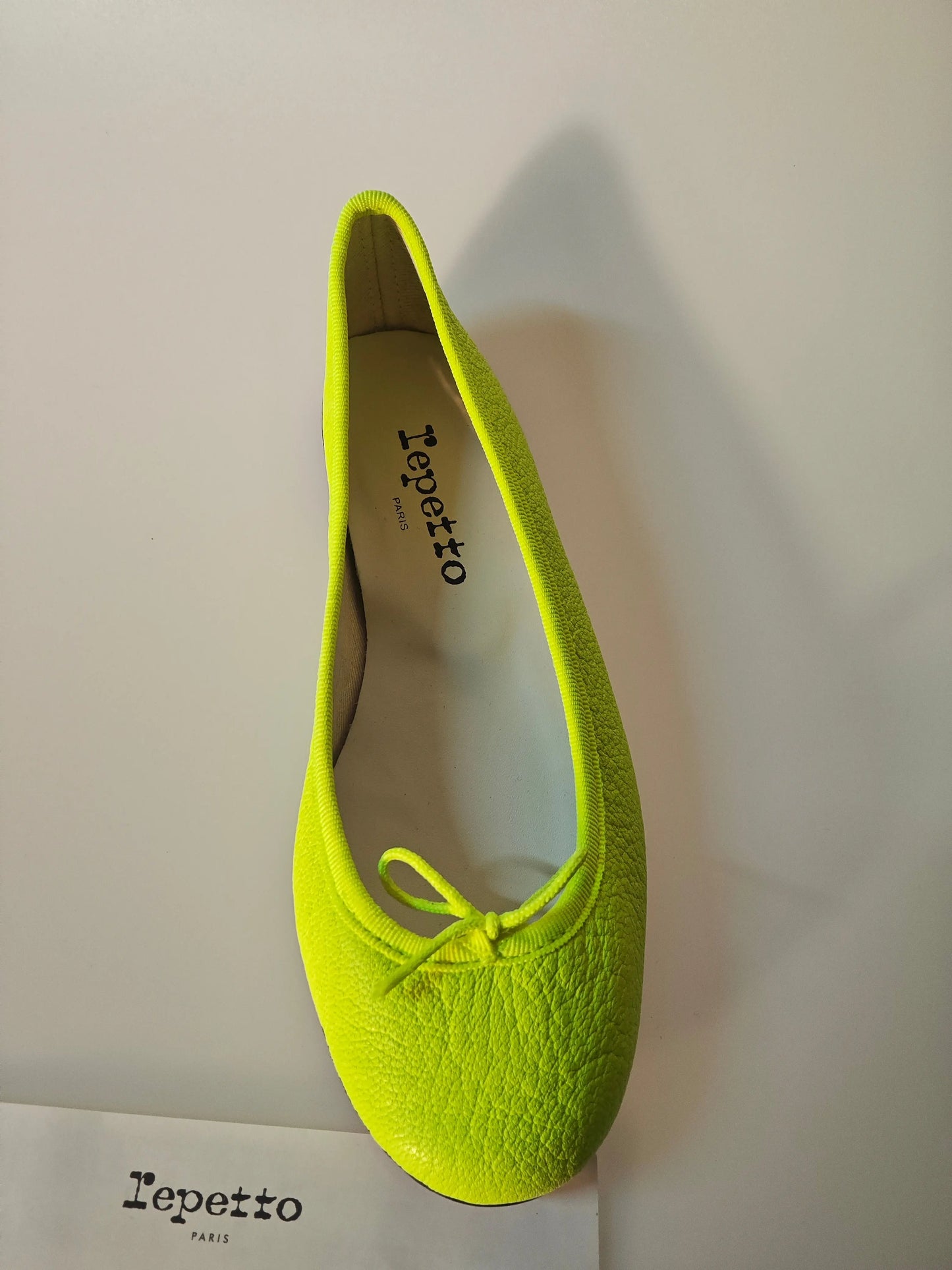 Ballerine jaune en cuir texturé de Repetto, avec lacet décoratif ton sur ton.
