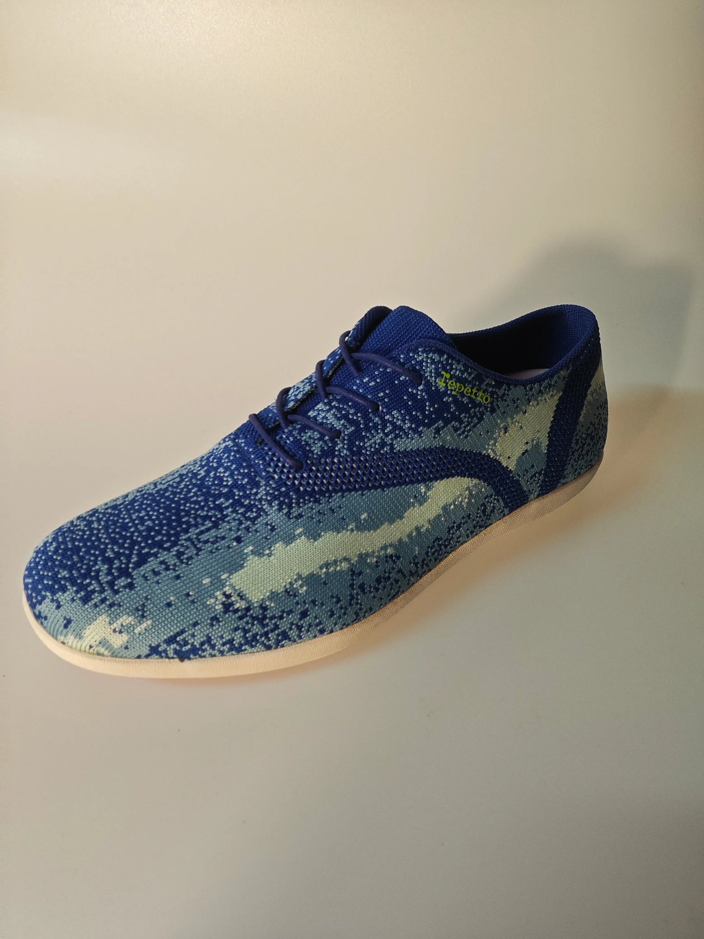 Chaussure de course bleue en maille par Repetto, avec un motif moucheté et des lacets bleus.
