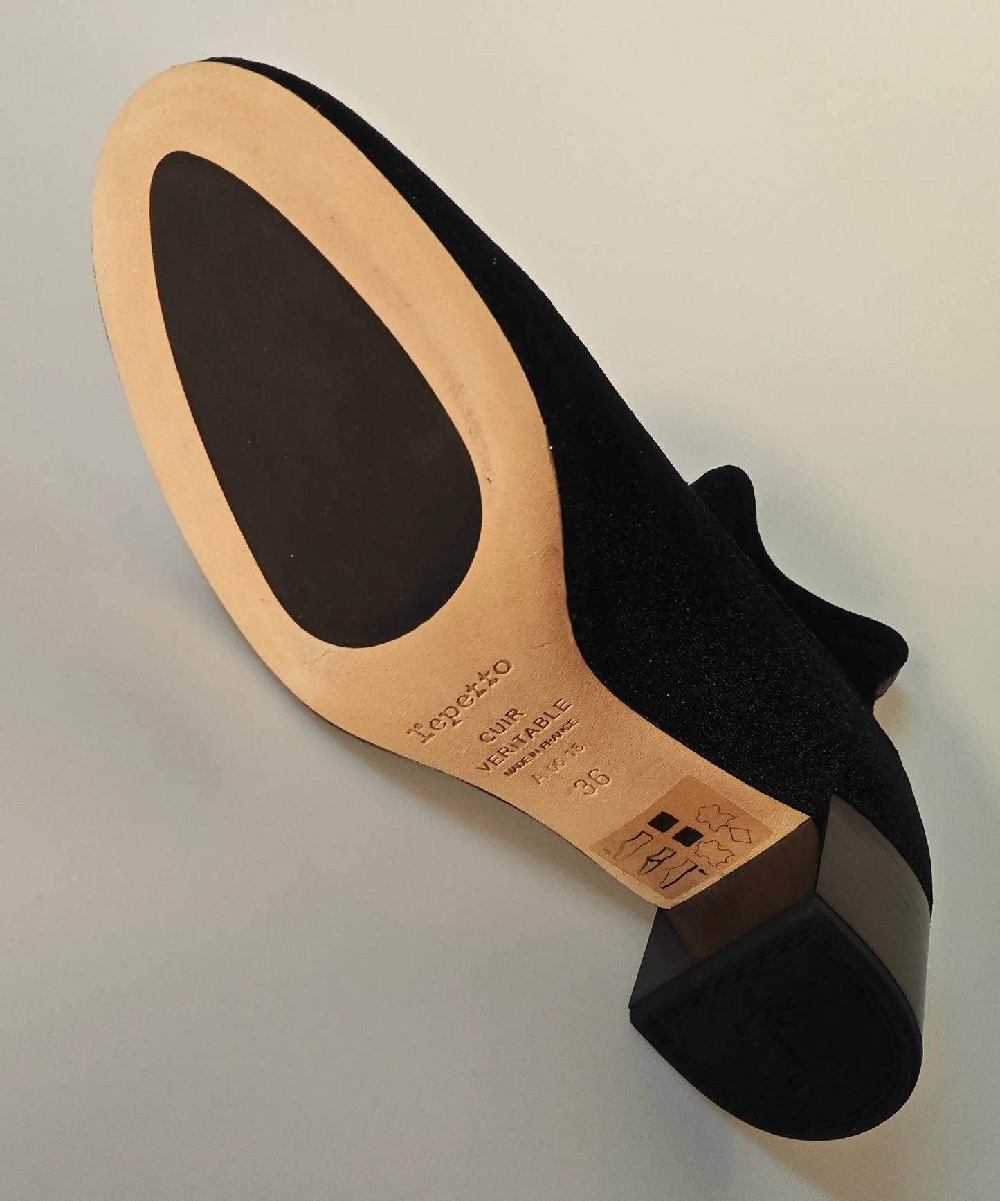 Bottines noires en velours, de Repetto, montrant la semelle en cuir clair avec une inscription et une talonnette noire.