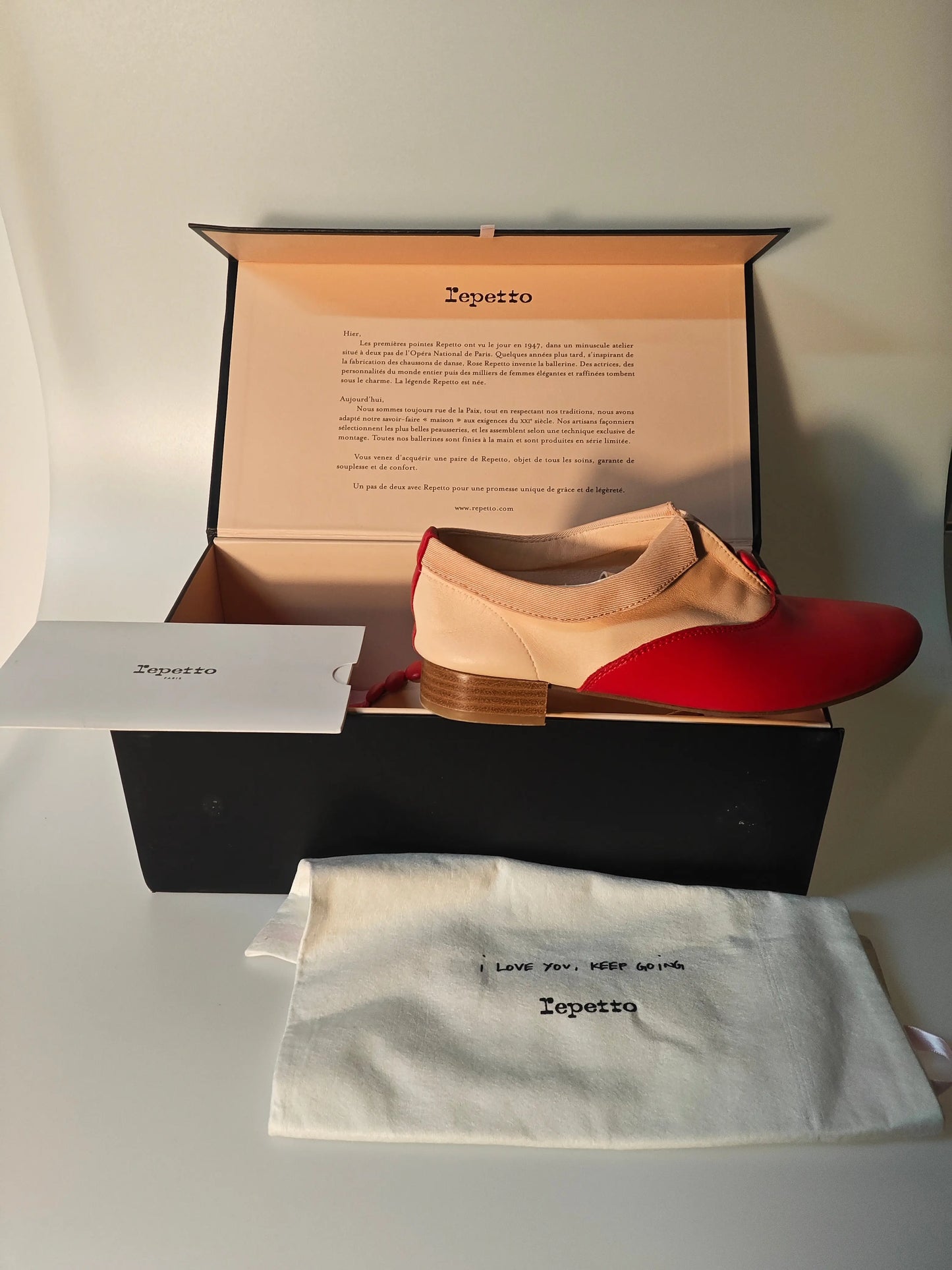 Chaussure Richelieu bicolore rouge et nude Repetto, issue de Repetto, présentée dans sa boîte avec son sac de rangement.

