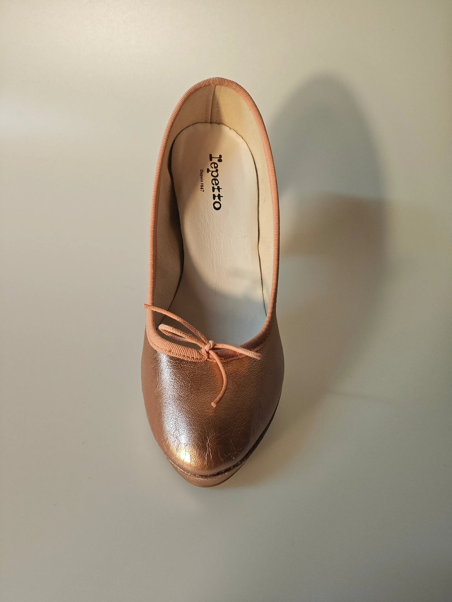 Ballerine en cuir rose cuivré par Repetto, avec un petit nœud décoratif ton sur ton.