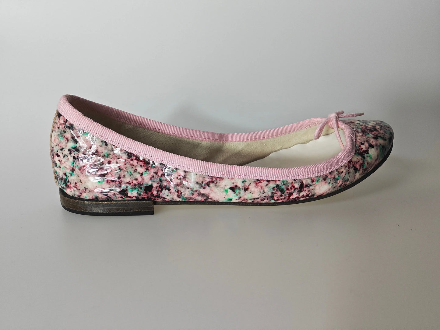 Ballerine vernie multicolore de Repetto, avec liseré rose et petit noeud décoratif.