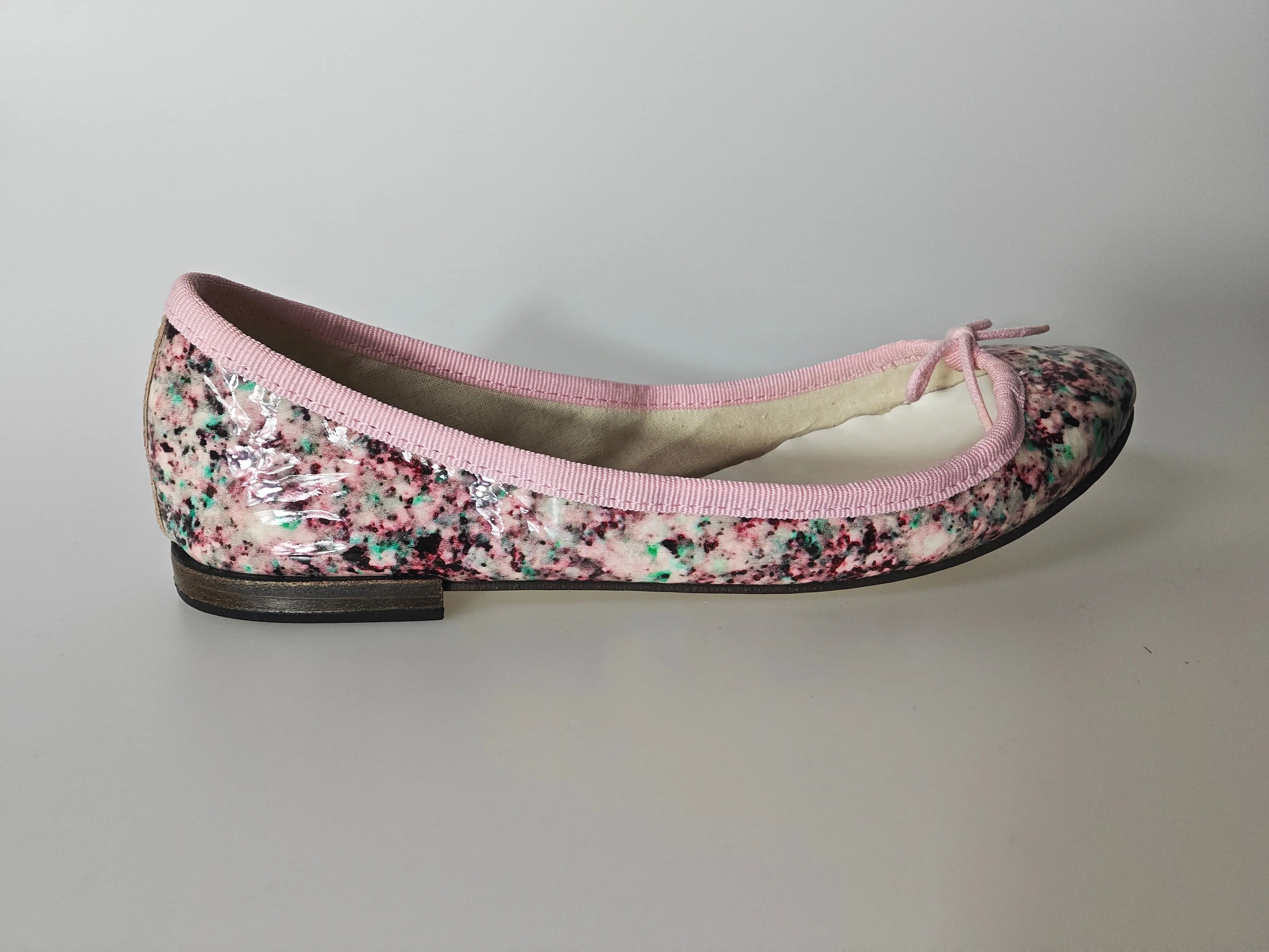 Ballerine vernie multicolore de Repetto, avec liseré rose et petit noeud décoratif.
