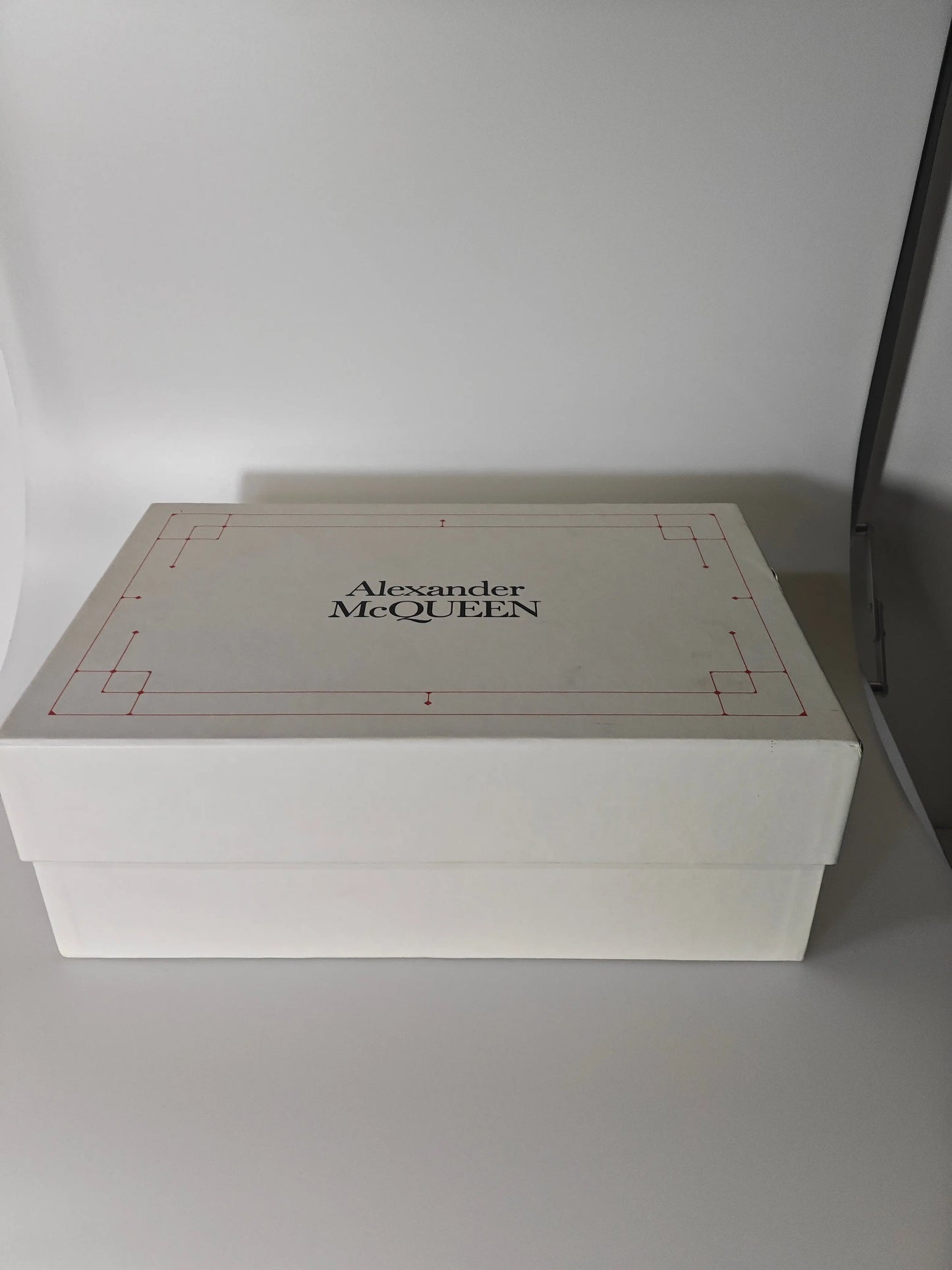 Boîte à chaussures blanche en cuir d'Alexander McQueen, avec motif géométrique rouge.