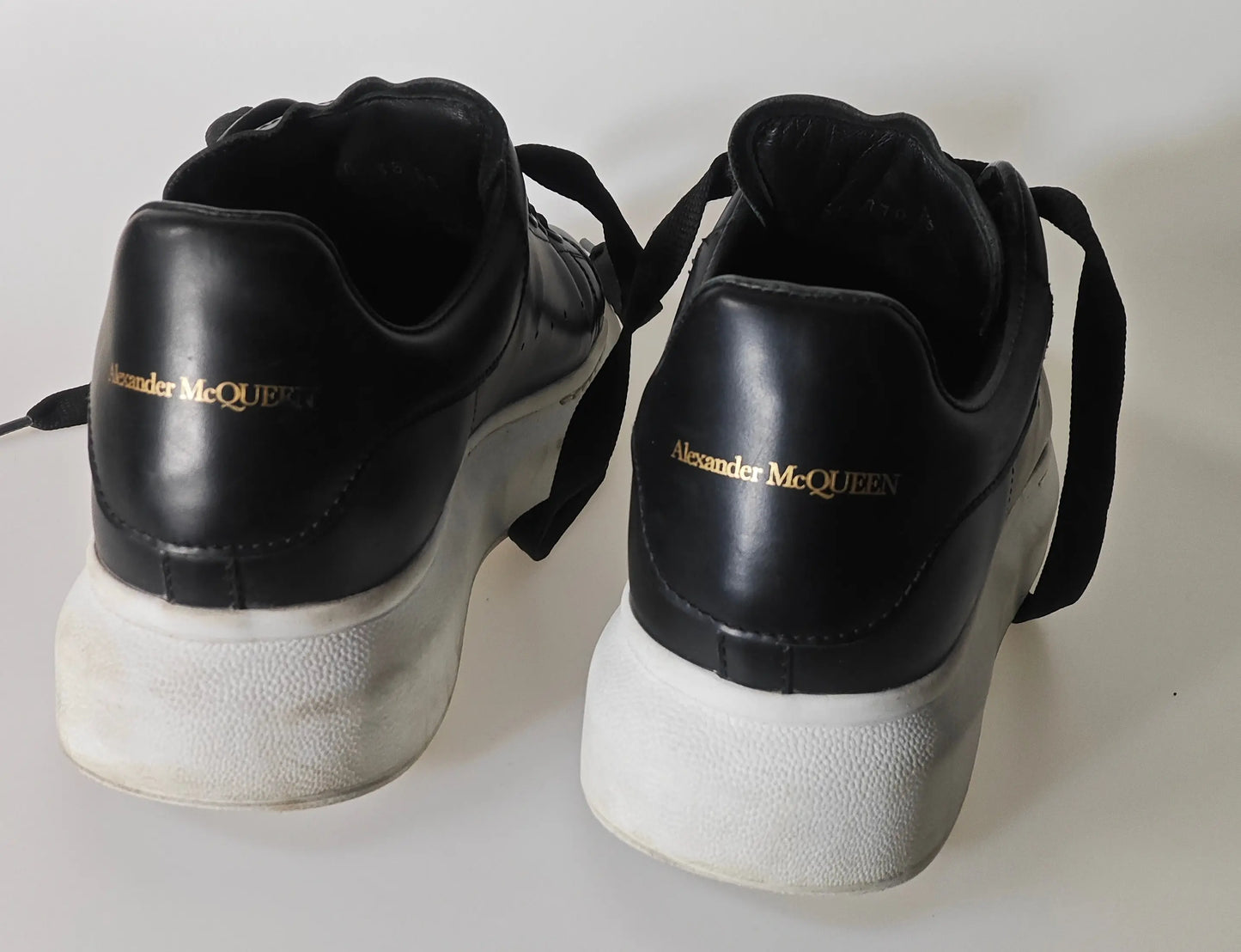Baskets en cuir noir par Alexander McQueen, avec semelles blanches épaisses et lacets noirs.