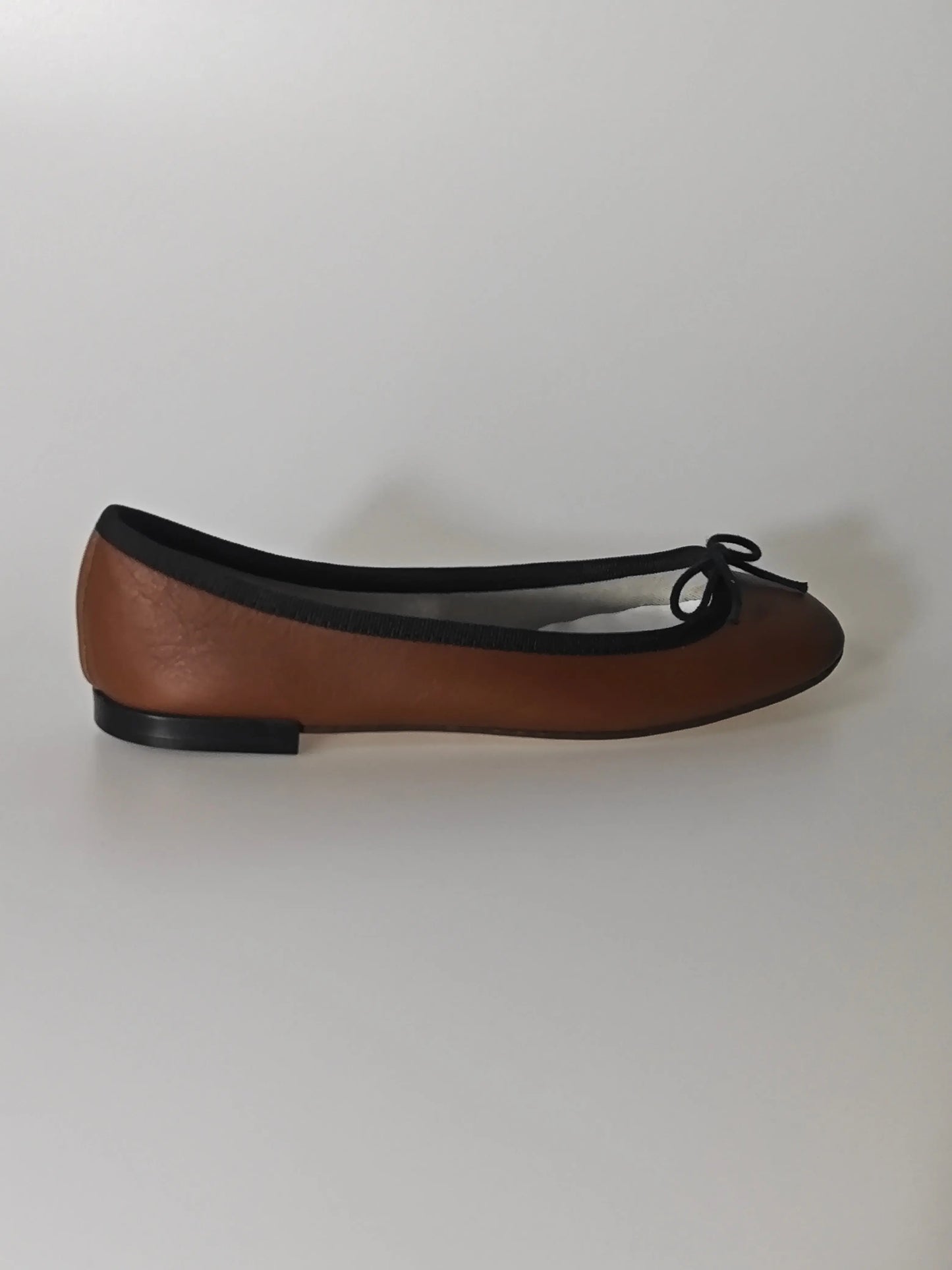 Ballerine marron Repetto, avec un liseré noir et un petit nœud décoratif.
