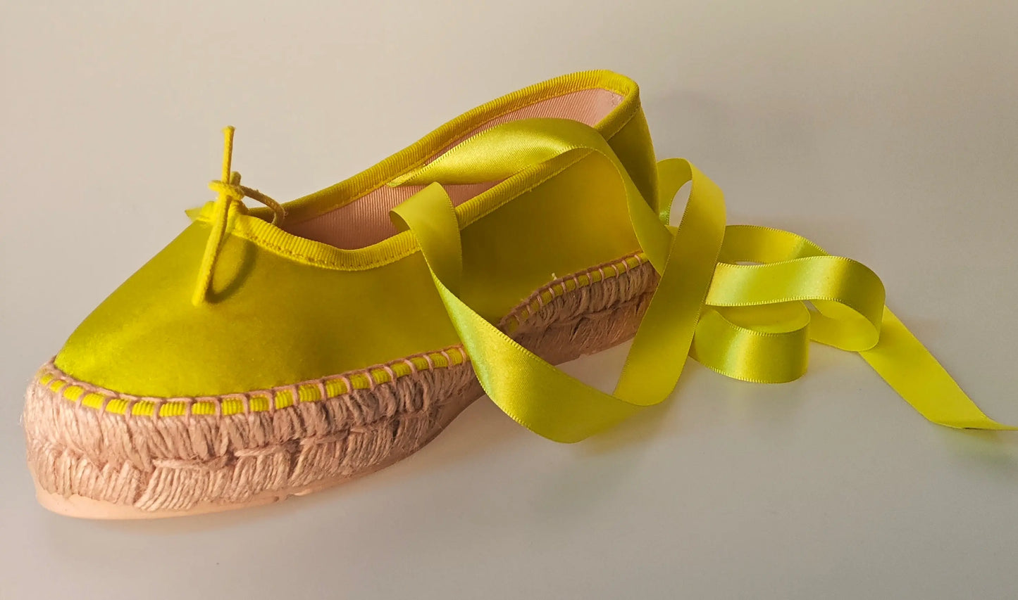Espadrille jaune en satin, de Repetto, avec ruban assorti enroulé autour, vue de côté.
