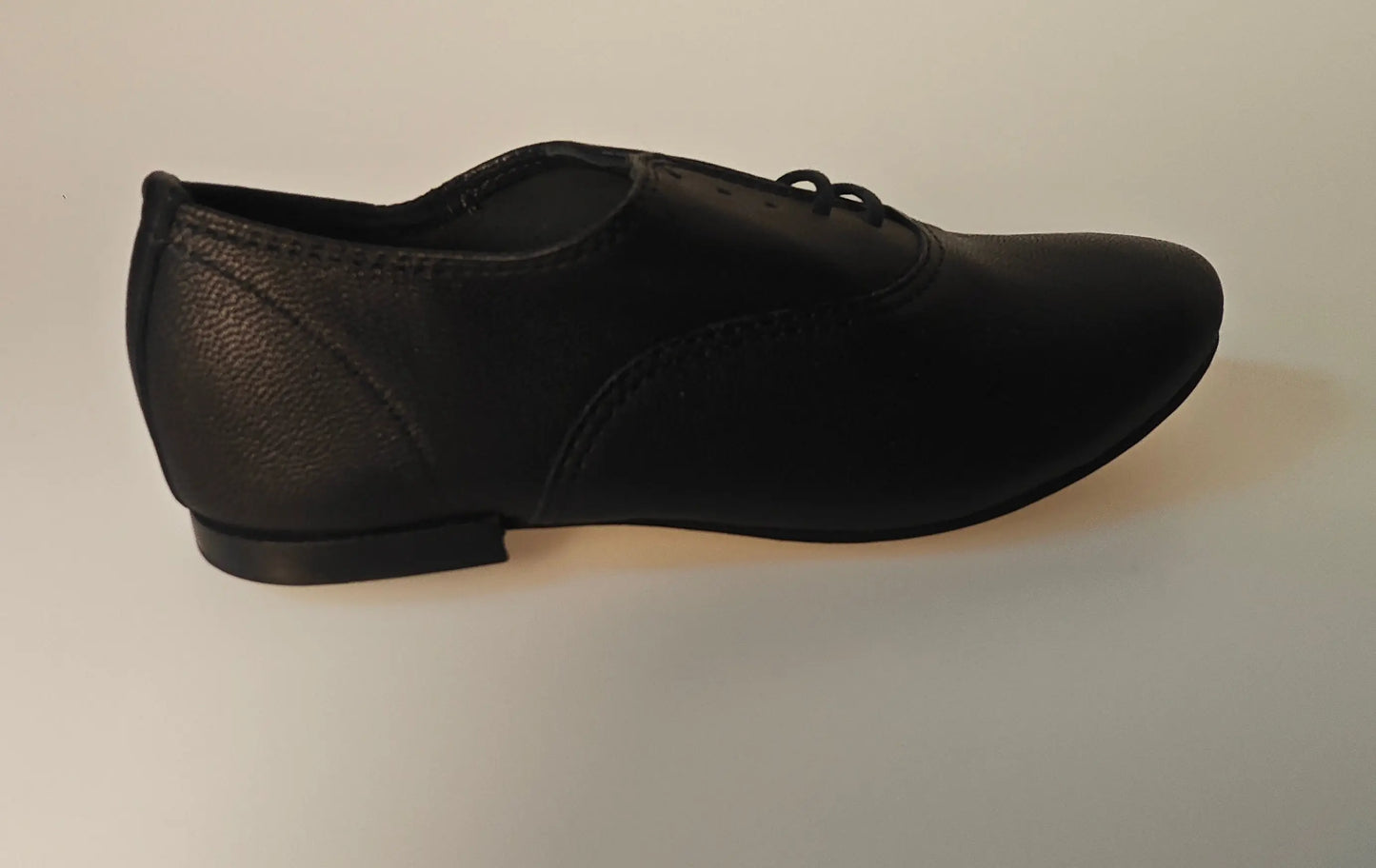 Richelieu Zizi en cuir noir par Repetto, avec un laçage fin et une texture grainée.

