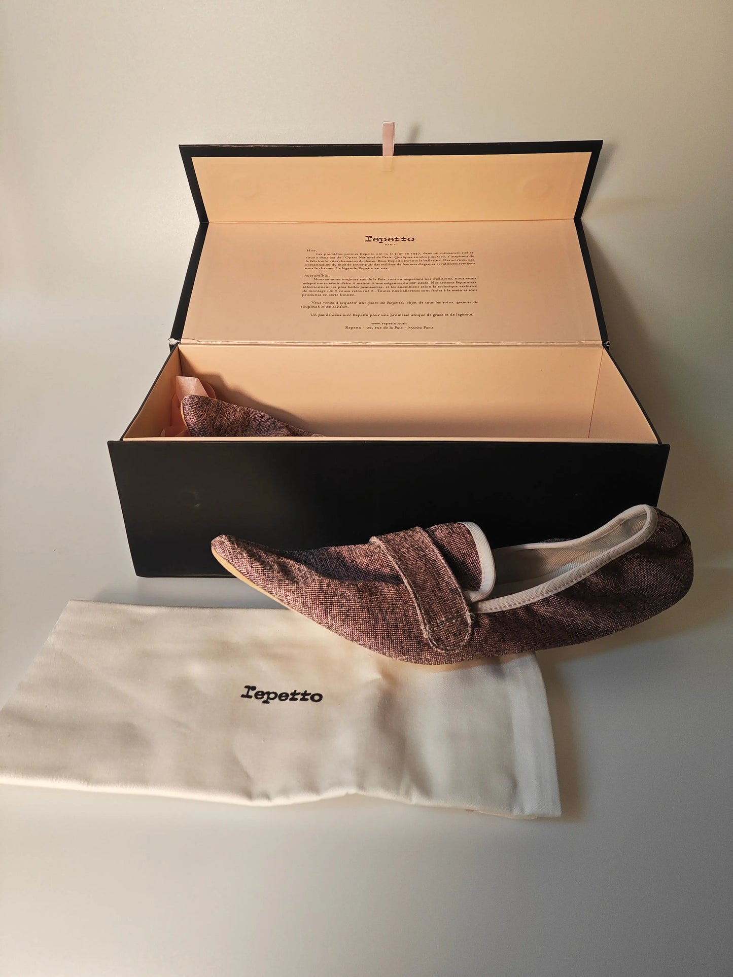 Ballerines marron à motif texturé Repetto dans leur boîte ouverte, avec un sac en tissu portant le logo.
