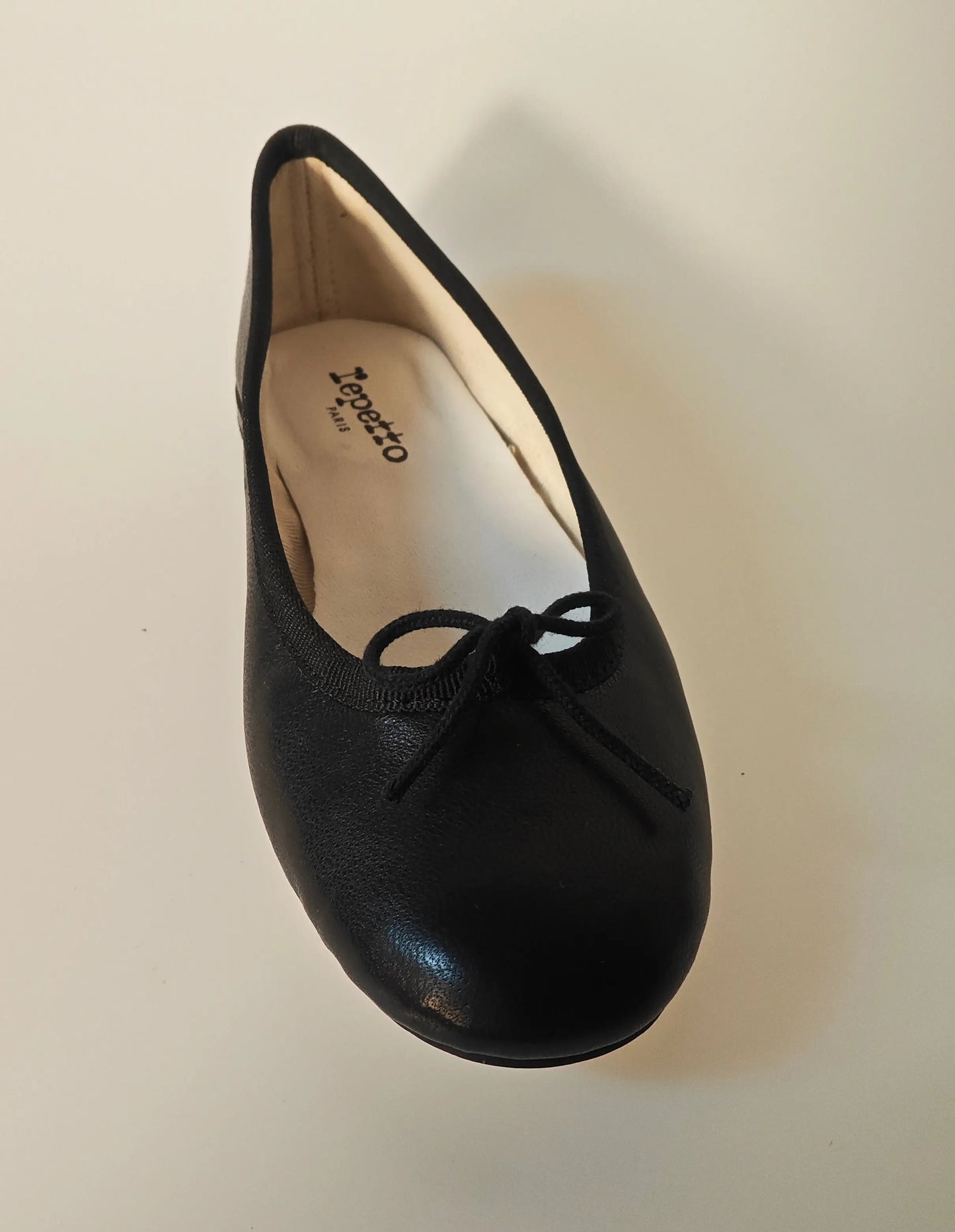 Ballerine noire en cuir véritable de Repetto, avec un petit nœud décoratif sur le dessus, vue de dessus.