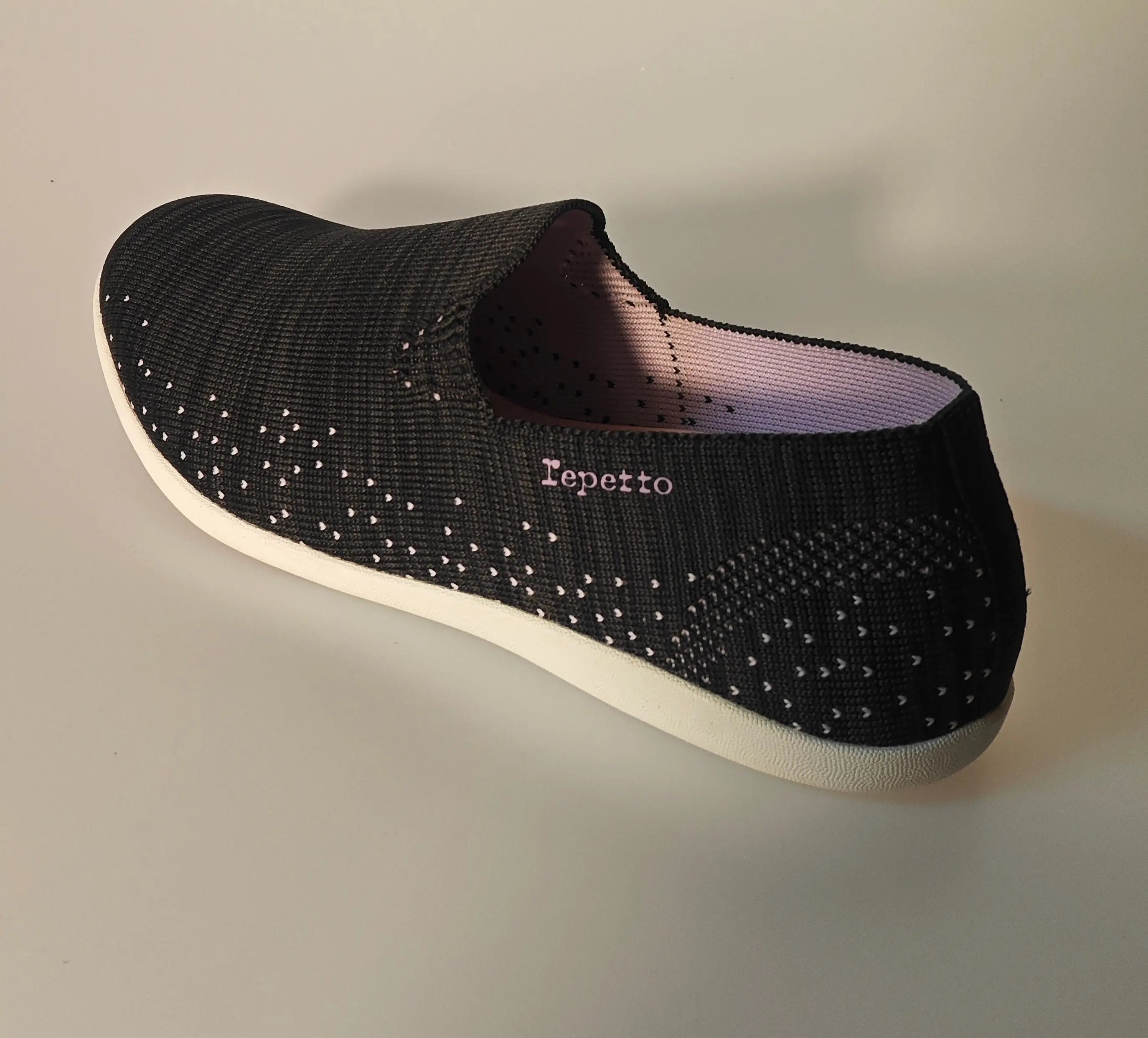Chaussure de course noire en maille par Repetto, avec motif pois et doublure rose, vue de côté.
