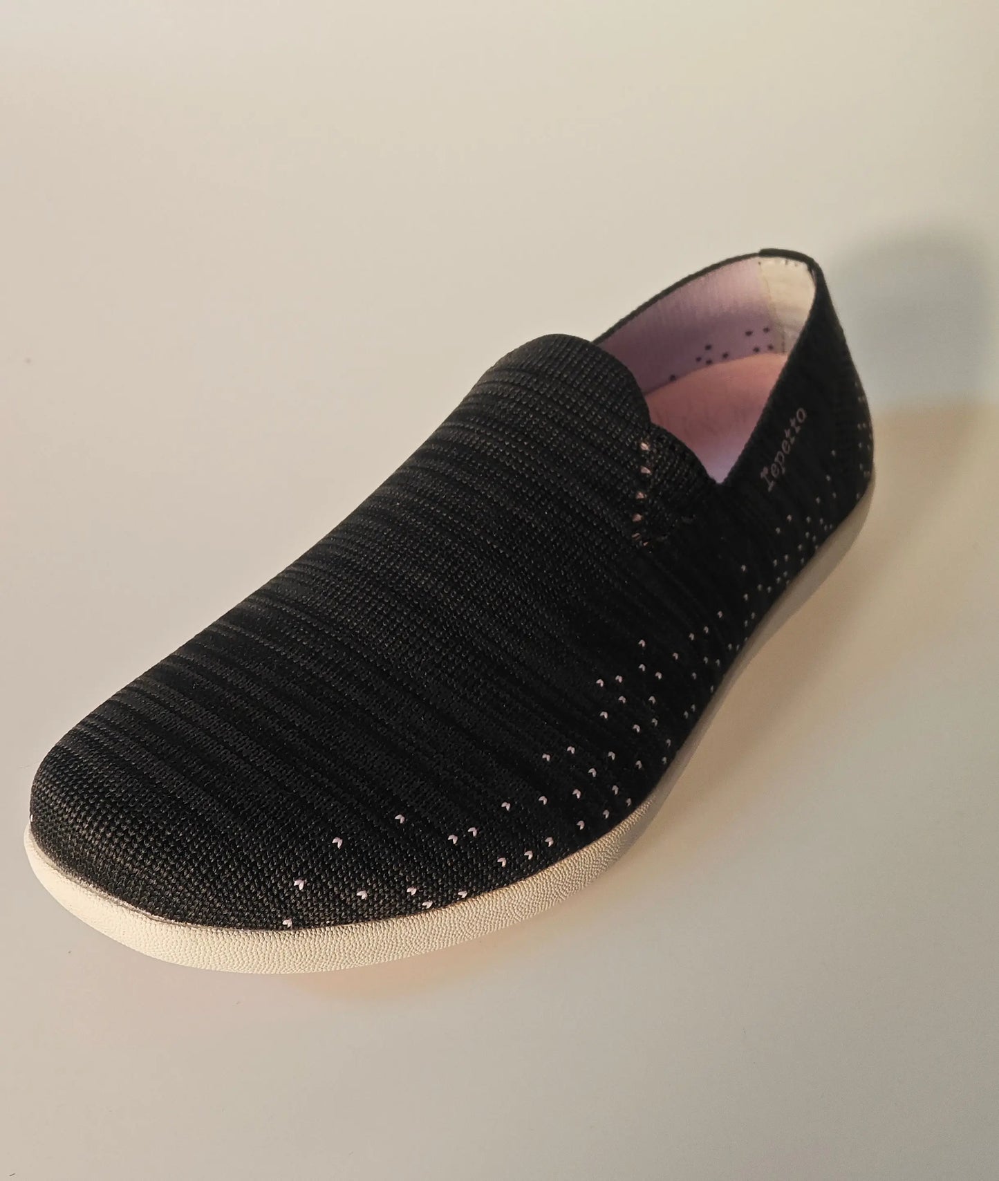 Mocassin noir en maille, de Repetto, avec motif de petits points roses sur la semelle texturée blanche.
