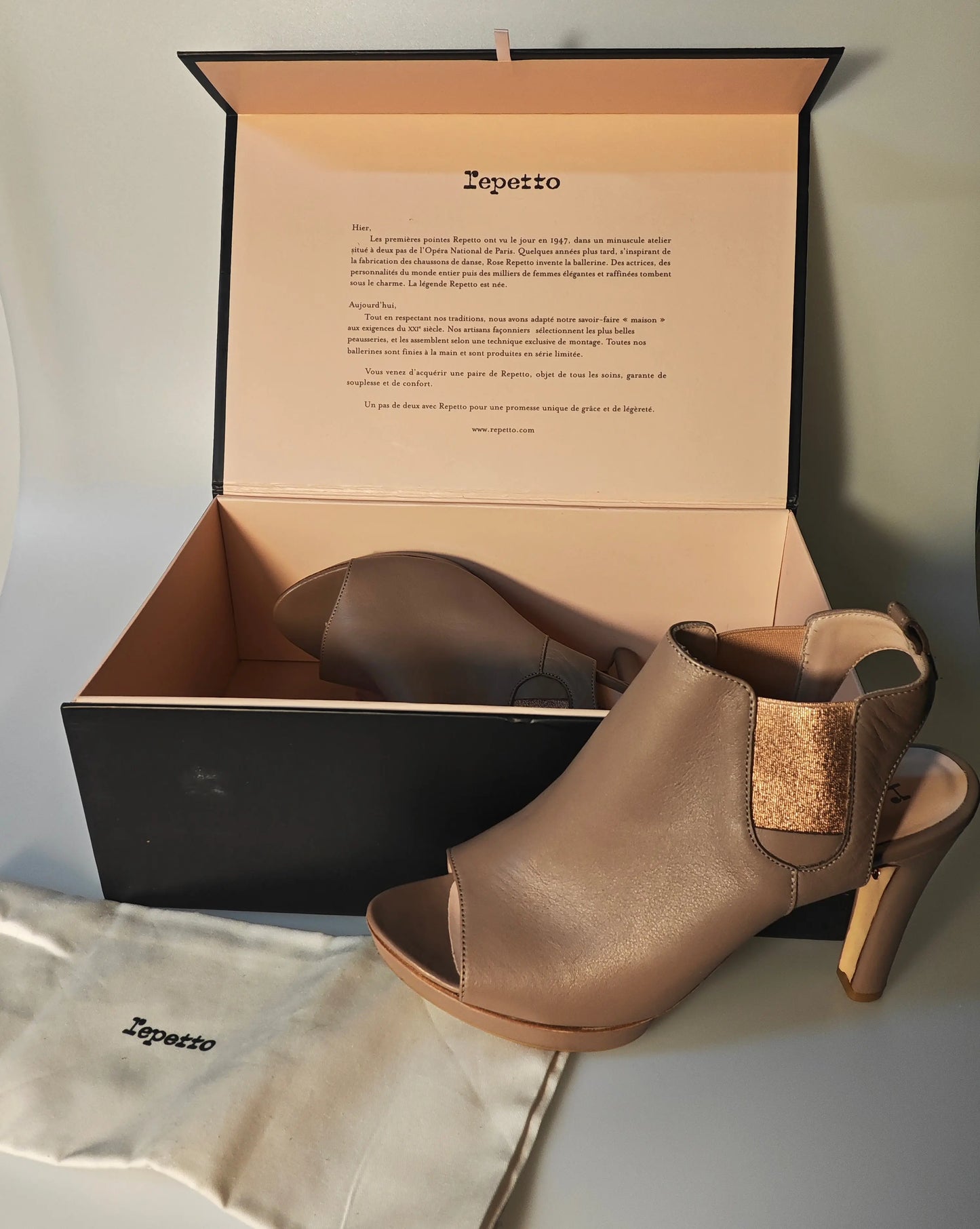 Sandales ouvertes en cuir couleur hermine de Repetto, avec élastique scintillant, présentées dans leur boîte et pochon logoté.
