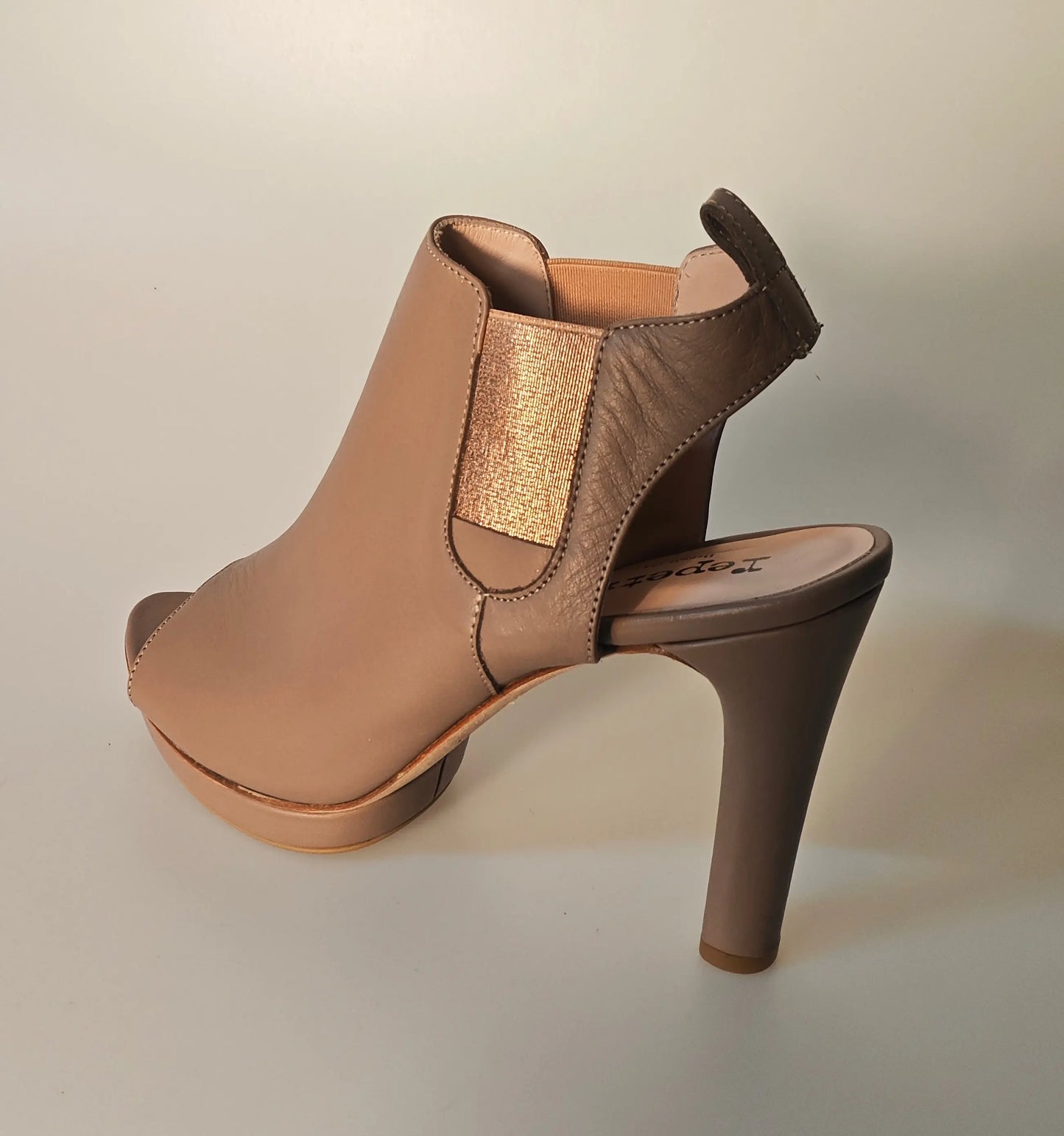 Sandale ouverte beige, de Repetto, avec talon aiguille et détail élastique doré.

