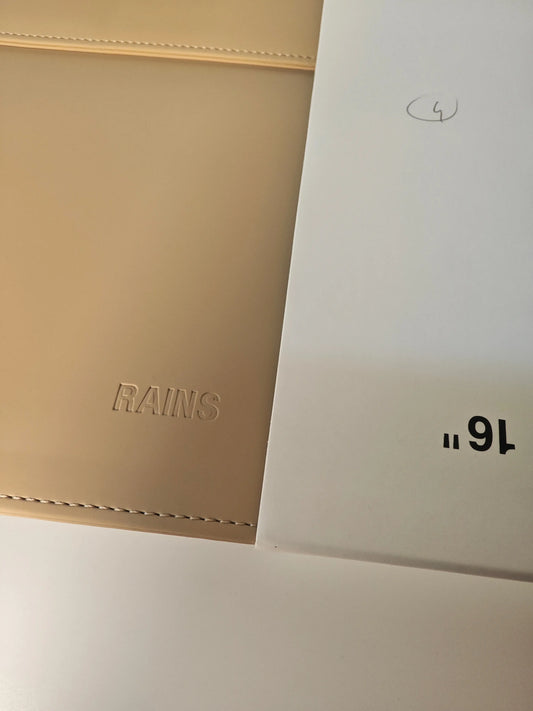 Housse d'ordinateur beige par Rains, avec couture apparente et inscription de la marque.