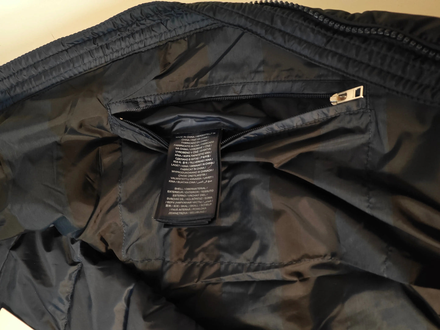 Doudoune sans manches bleu marine de Gant avec une poche zippée visible et une étiquette d'information.

