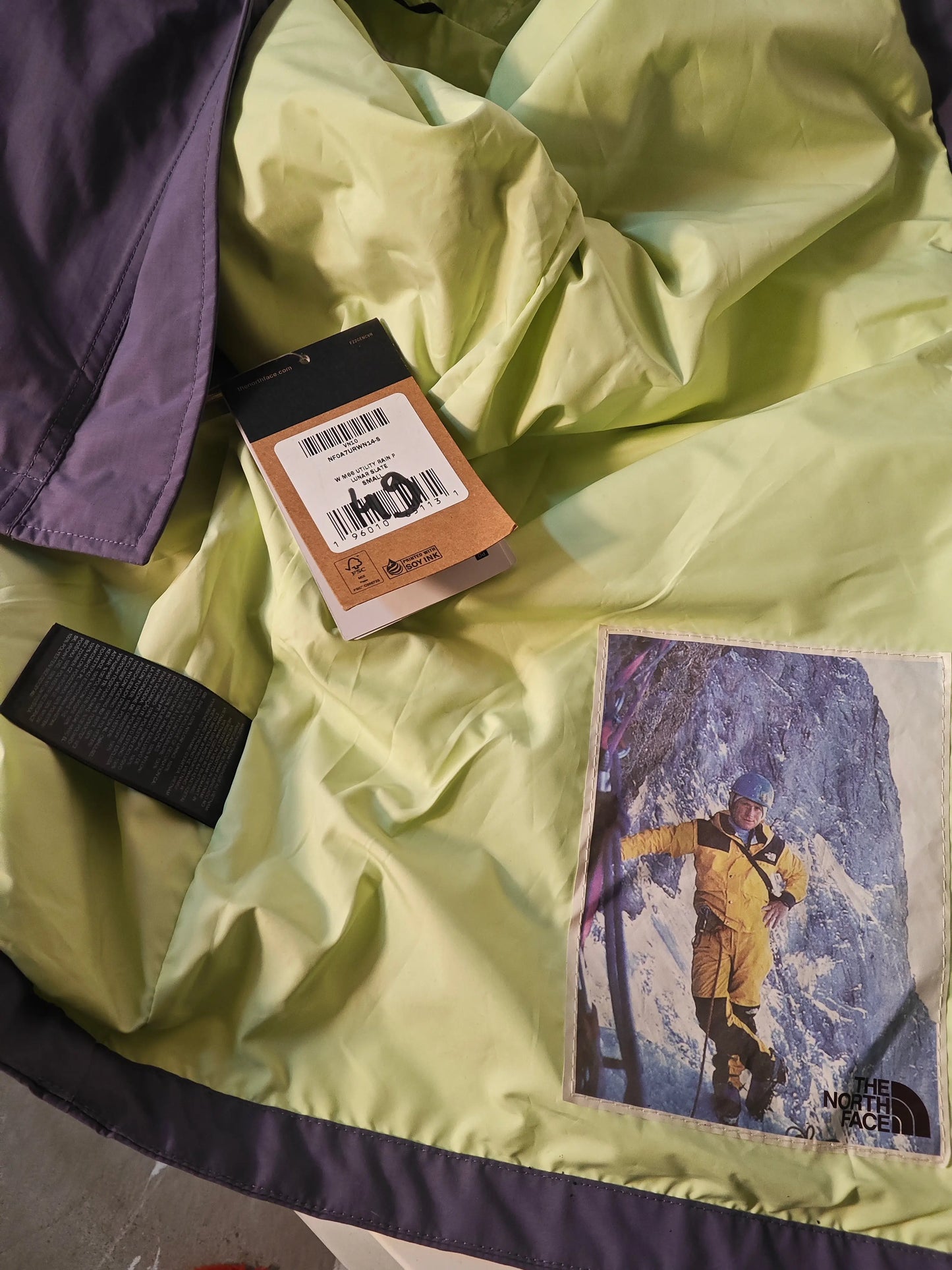 Veste parka de pluie violette lavande et menthe, DryVent de The North Face, avec une étiquette et une photo cousue.
