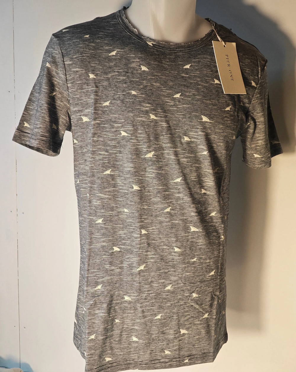 T-shirt gris à motifs voiliers de Pier One, sur un mannequin, avec un col usé.
