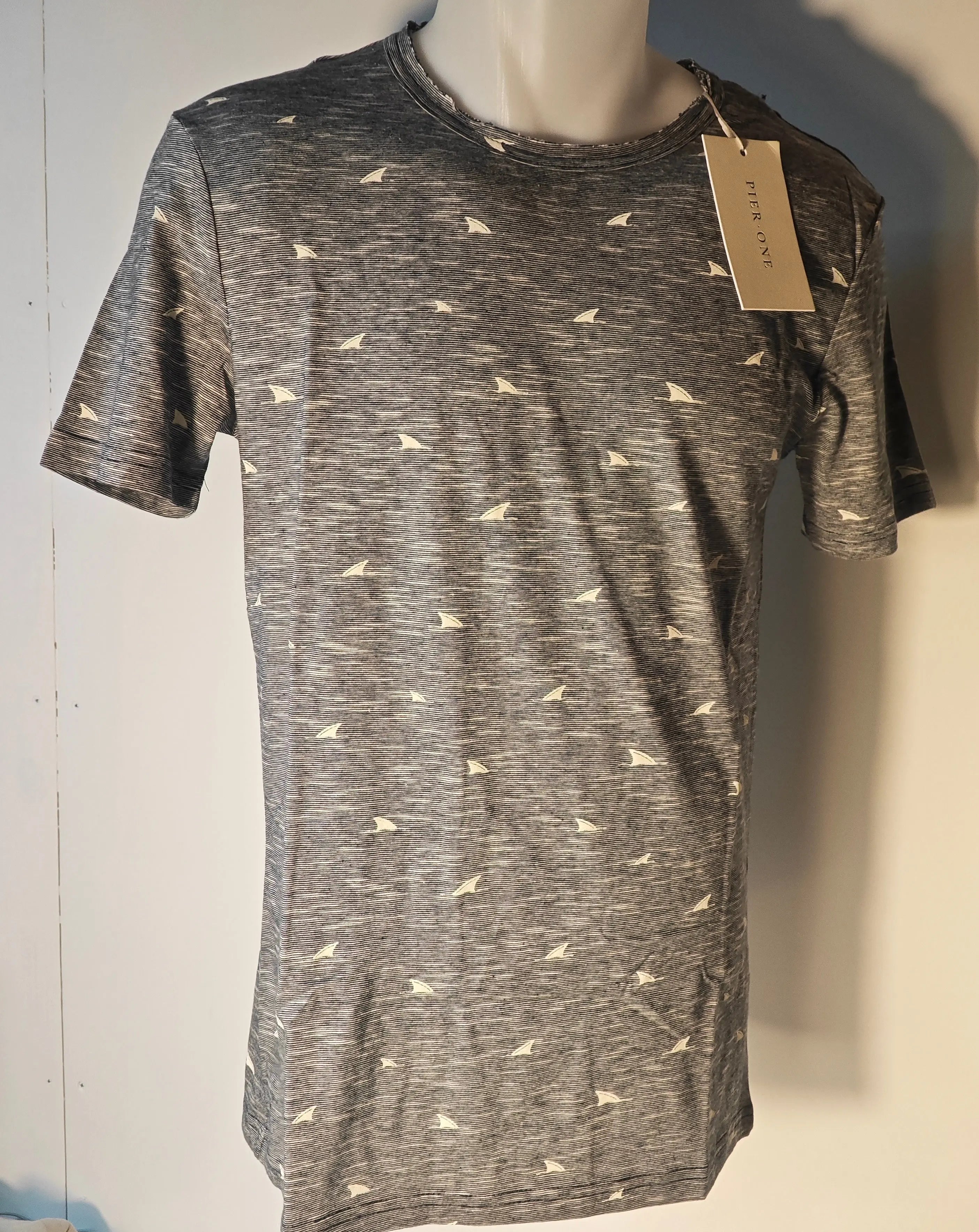 T-shirt gris à motifs voiliers de Pier One, sur un mannequin, avec un col usé.
