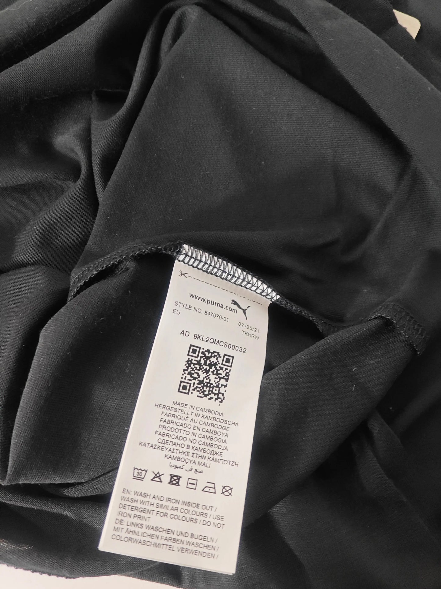 T-shirt noir à logo argenté DRYCELL, de Puma, avec étiquette d'entretien visible.
