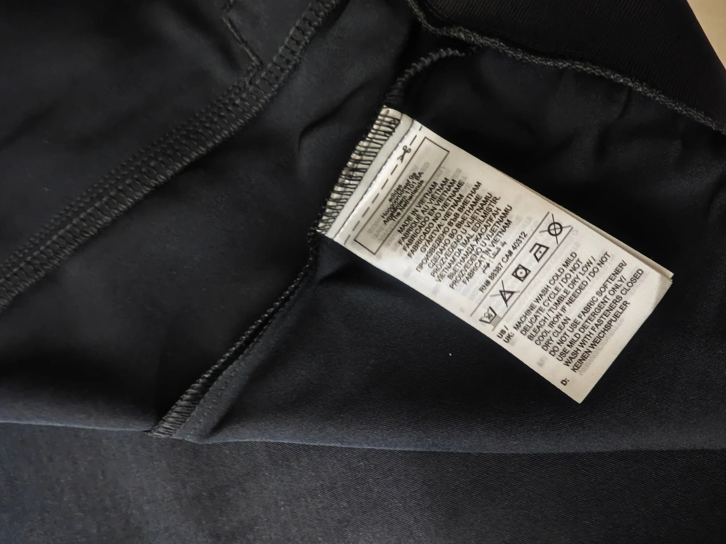 Veste noire en satin Originals SST de Adidas, montrant l'étiquette d'entretien cousue sur le vêtement.
