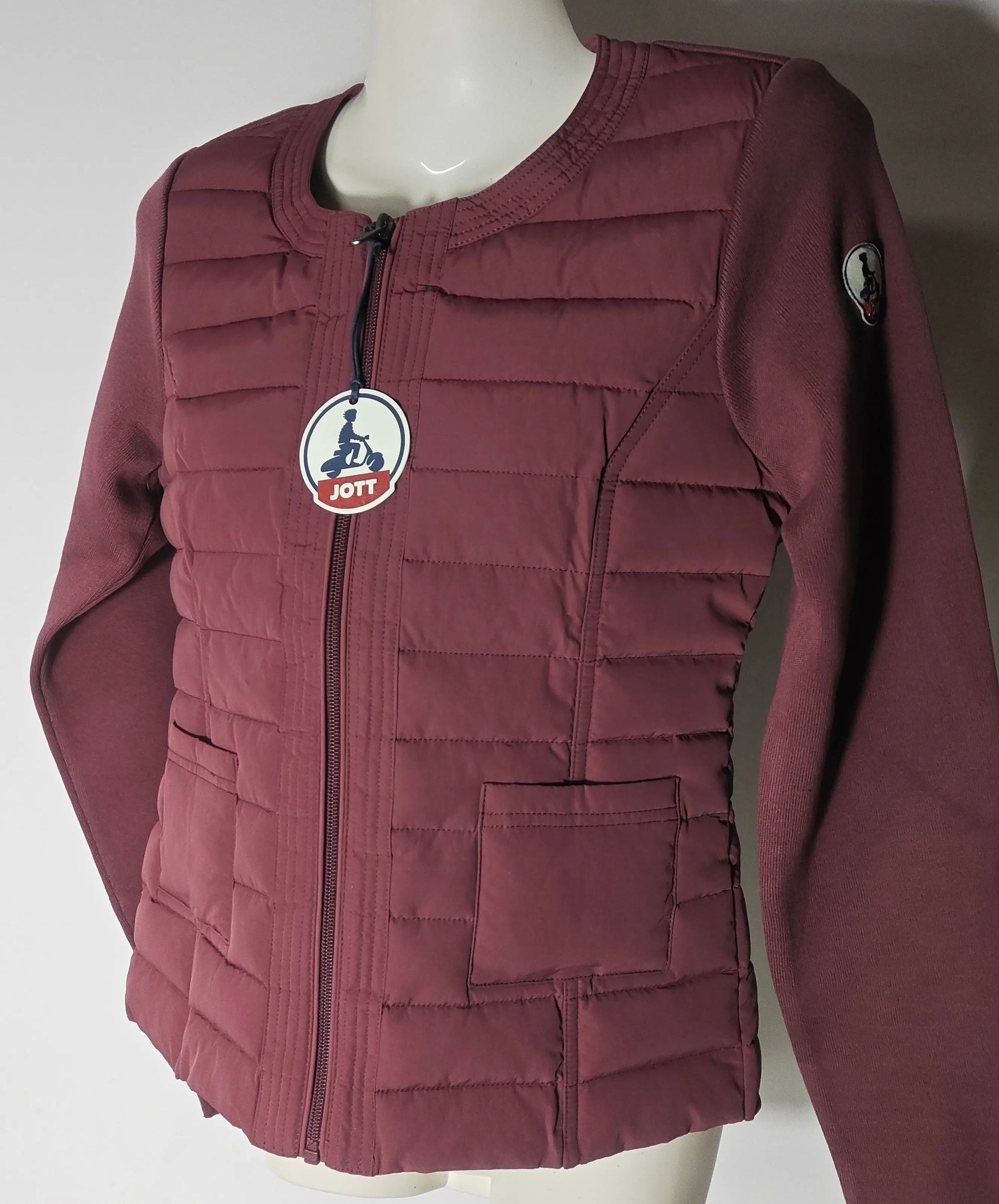 Veste matelassée bordeaux JOTT avec manches longues en tricot, et logo sur la manche.