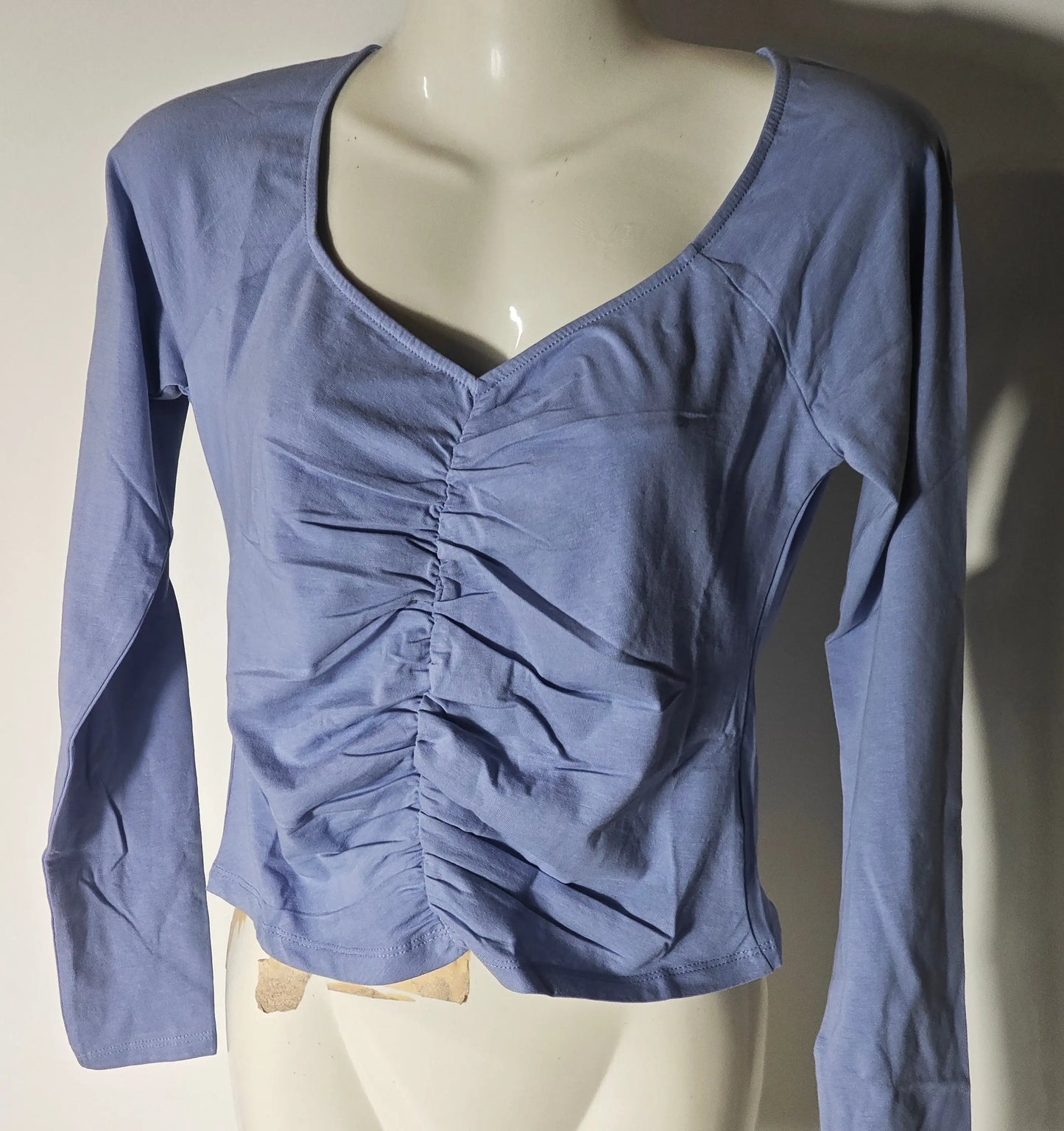 Haut bleu froncé by Monki, à manches longues et encolure en V, présenté sur un mannequin buste.