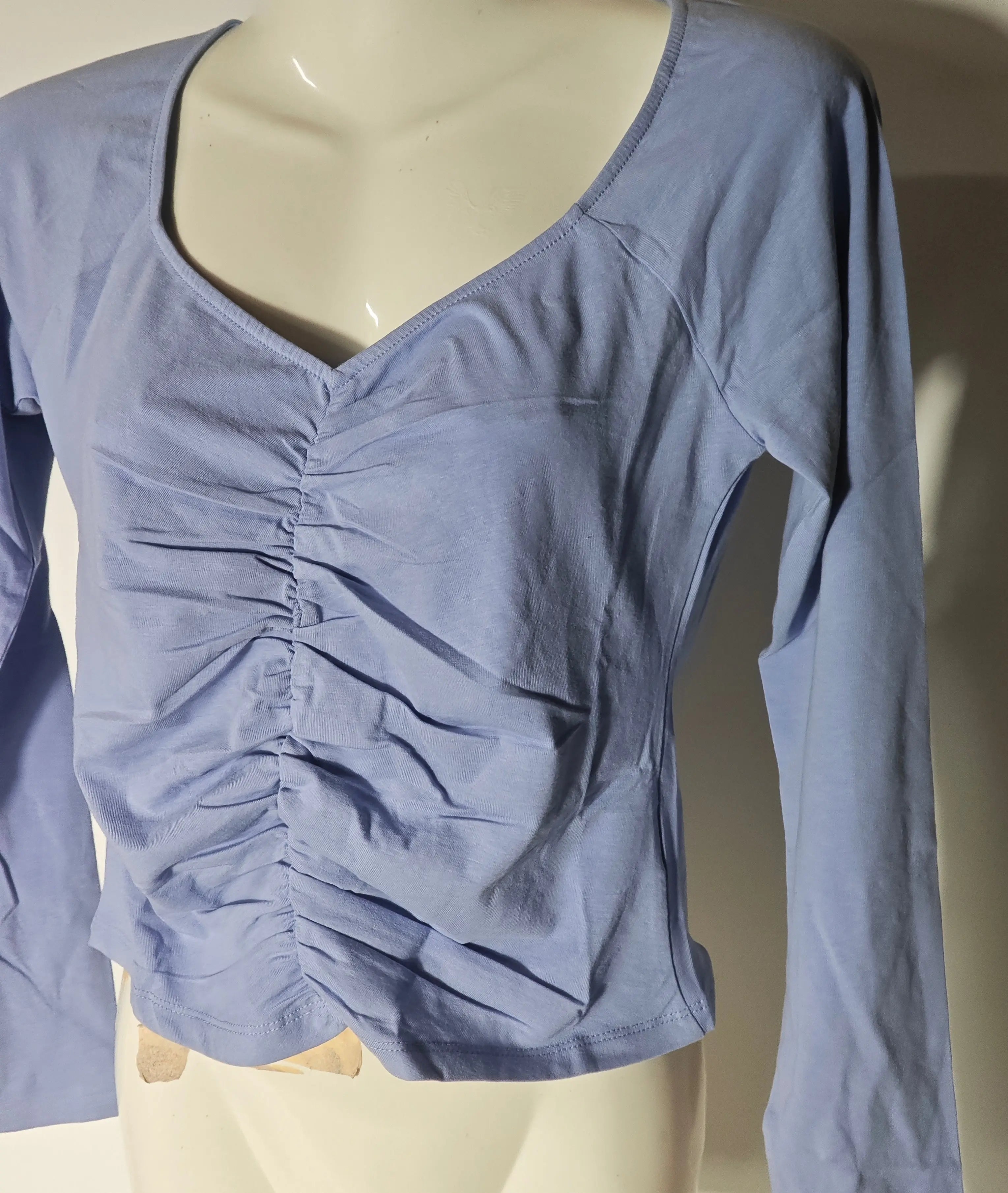 Haut bleu froncé de Monki avec encolure en V et manches longues, présenté sur un mannequin.
