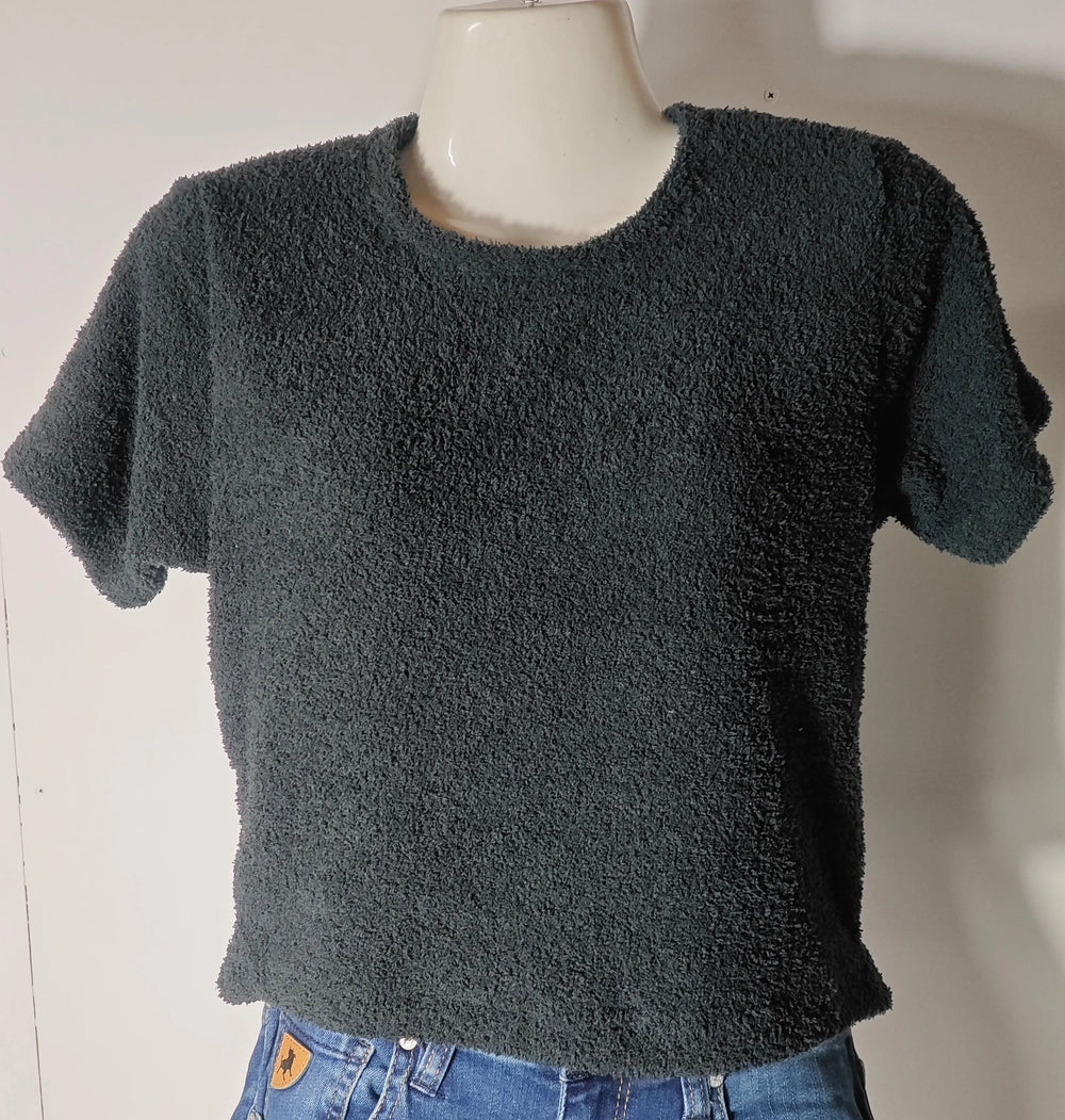 Crop top noir effet éponge Fila, porté sur un mannequin, avec un jean taille basse visible.