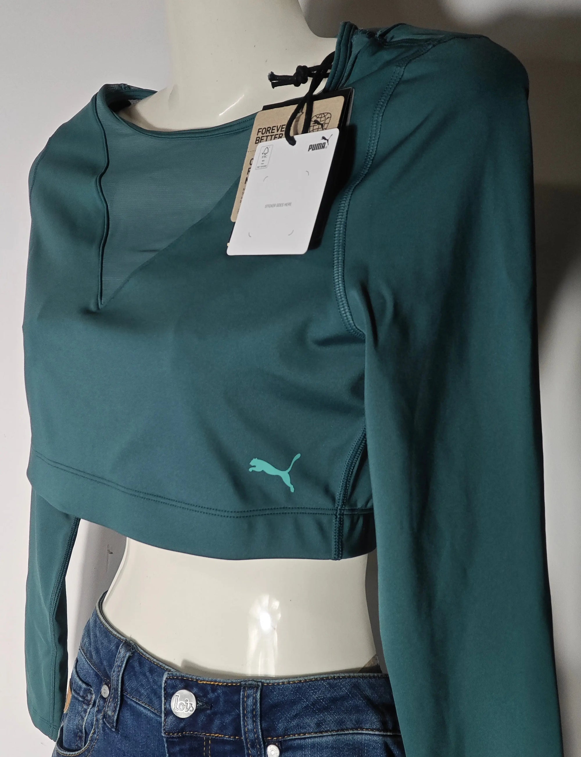 Crop top de sport à manches longues vert tight fit par Puma, porté avec un jean taille basse.