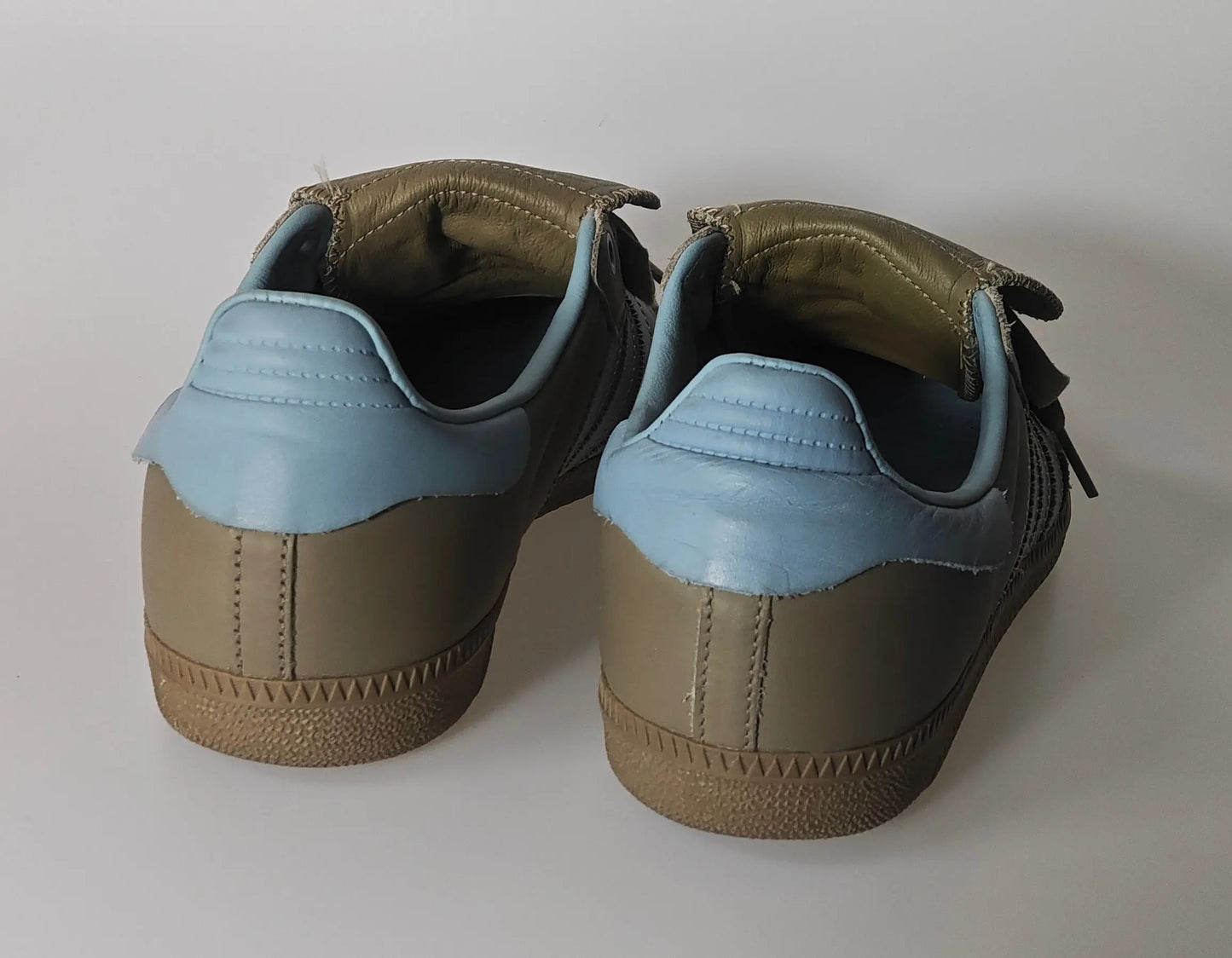 Sneakers Samba Humanrace beiges et bleues d'Adidas par Pharrell Williams, présentées de dos.