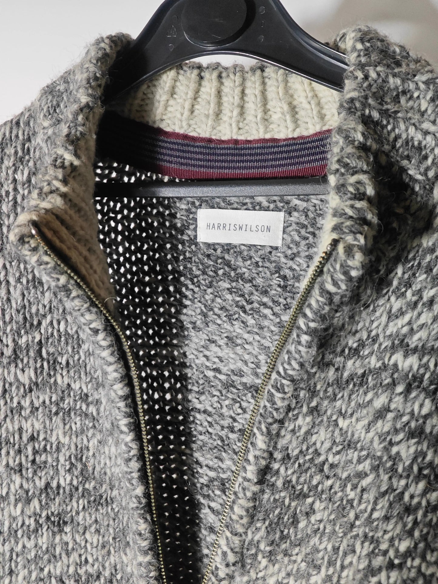 Gilet zippé en laine épaisse gris chiné de Harris Wilson, sur cintre noir, maille tricotée grossière.
