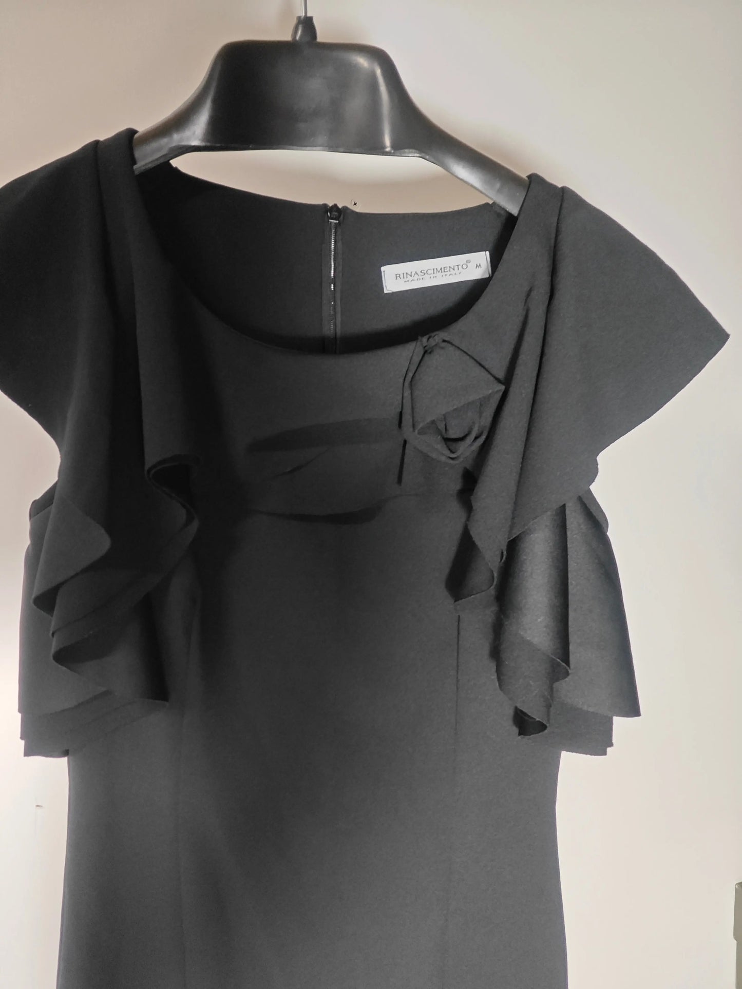 Robe noire élégante à volants de Rinascimento, confectionnée en Italie, avec fermeture éclair discrète et détail de nœud décoratif.
