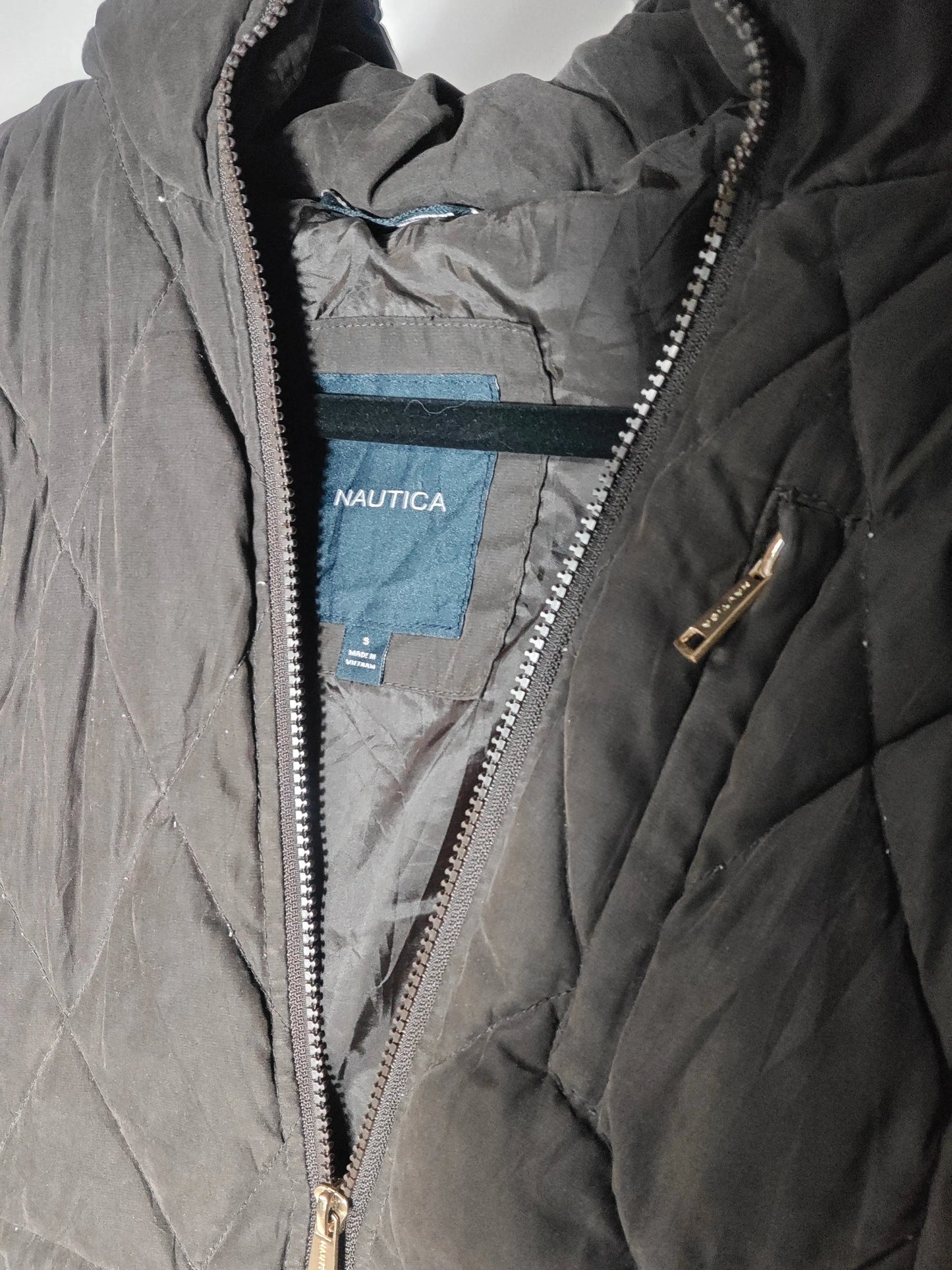 Veste chaude noire de Nautica, matelassée avec fermeture éclair, présentée sur un cintre.