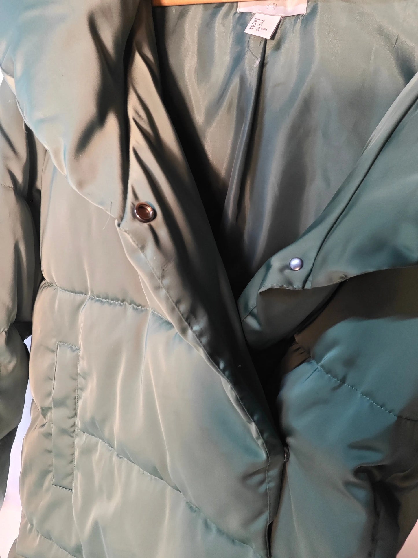 Doudoune verte de H&M avec boutons-pression sur le col, poche plaquée et matelassage.